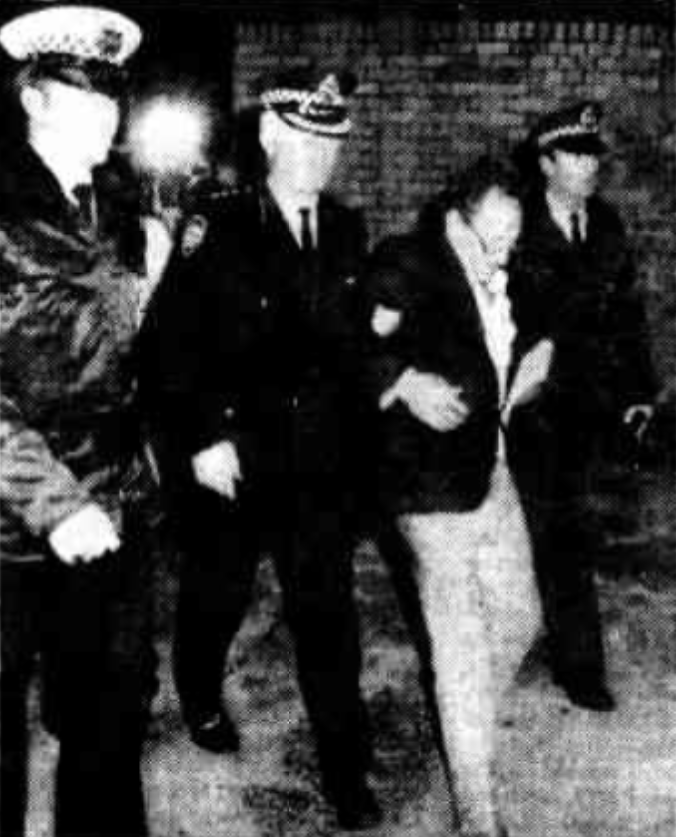 Mr O'Shannassy is escorted to a waiting police car.