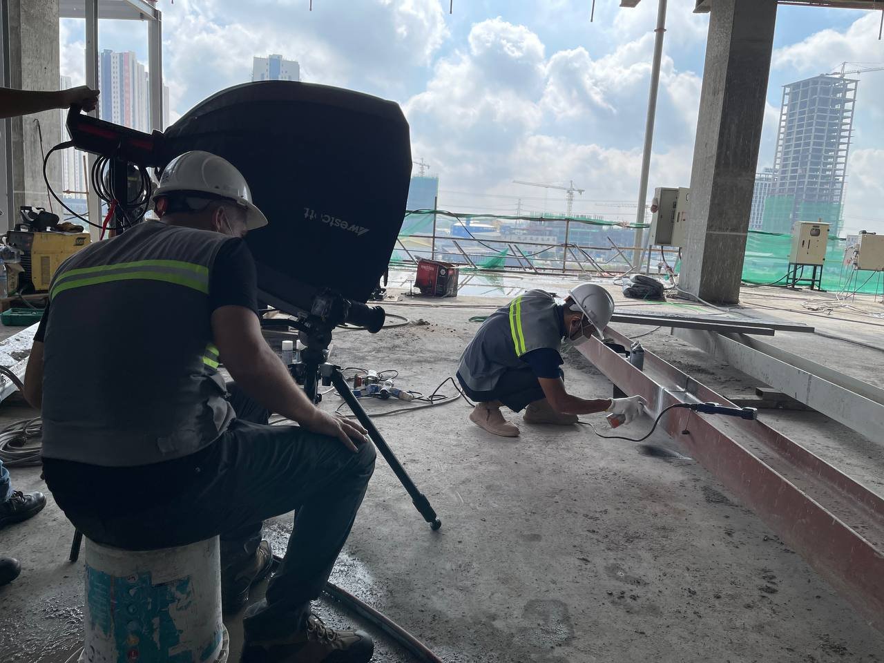 George filming a wide shot of non-destructive steel testing on a building site in Phnom Penh for a corporate video