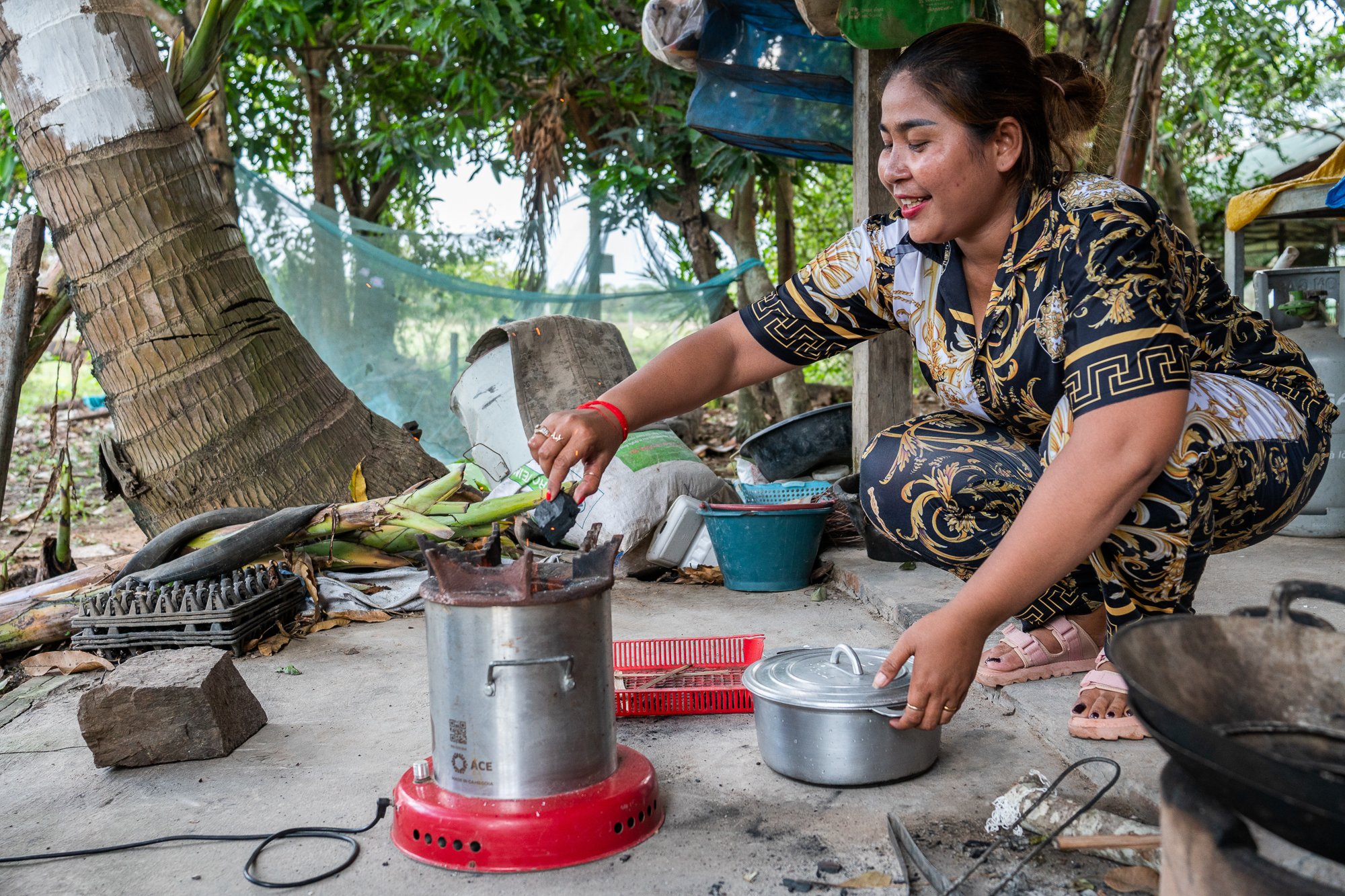 Leam Salao puts wood on her stove bought using a loan from NGO Kiva, Siem Reap, Cambodia 