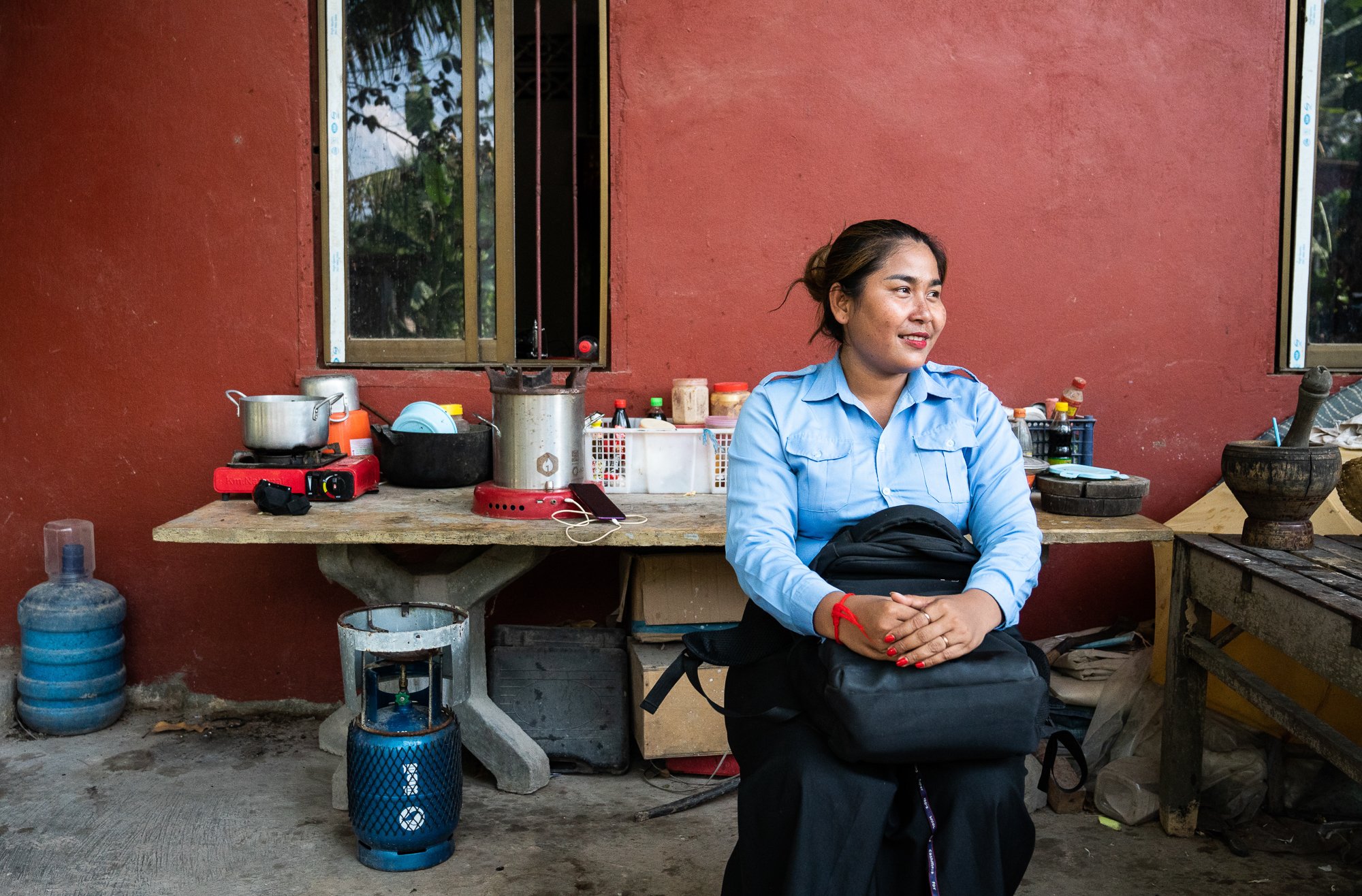 Leam Salao sits outside her house by her ACE stove she bought using a loan from the NGO Kiva
