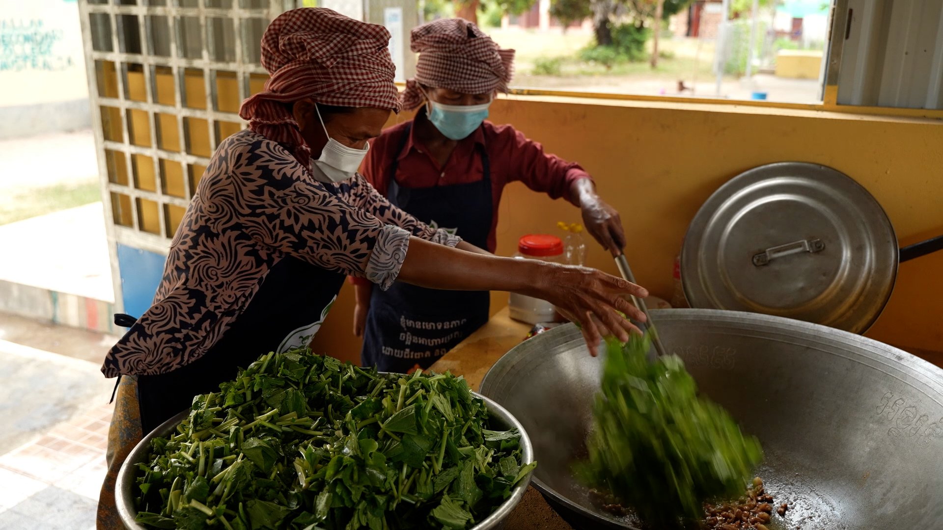 School cooks cook vegetables. Frame grab while working as an NGO videographer for WFP Cambodia