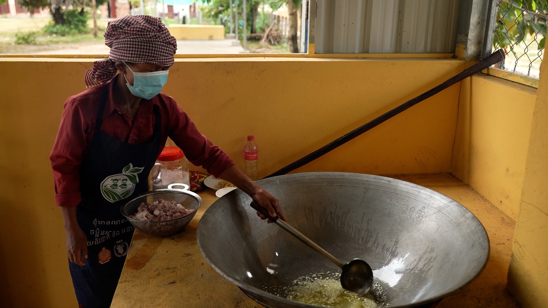 Cook stirs garlic. Frame grab working as a camera operator for WFP in Siem Reap