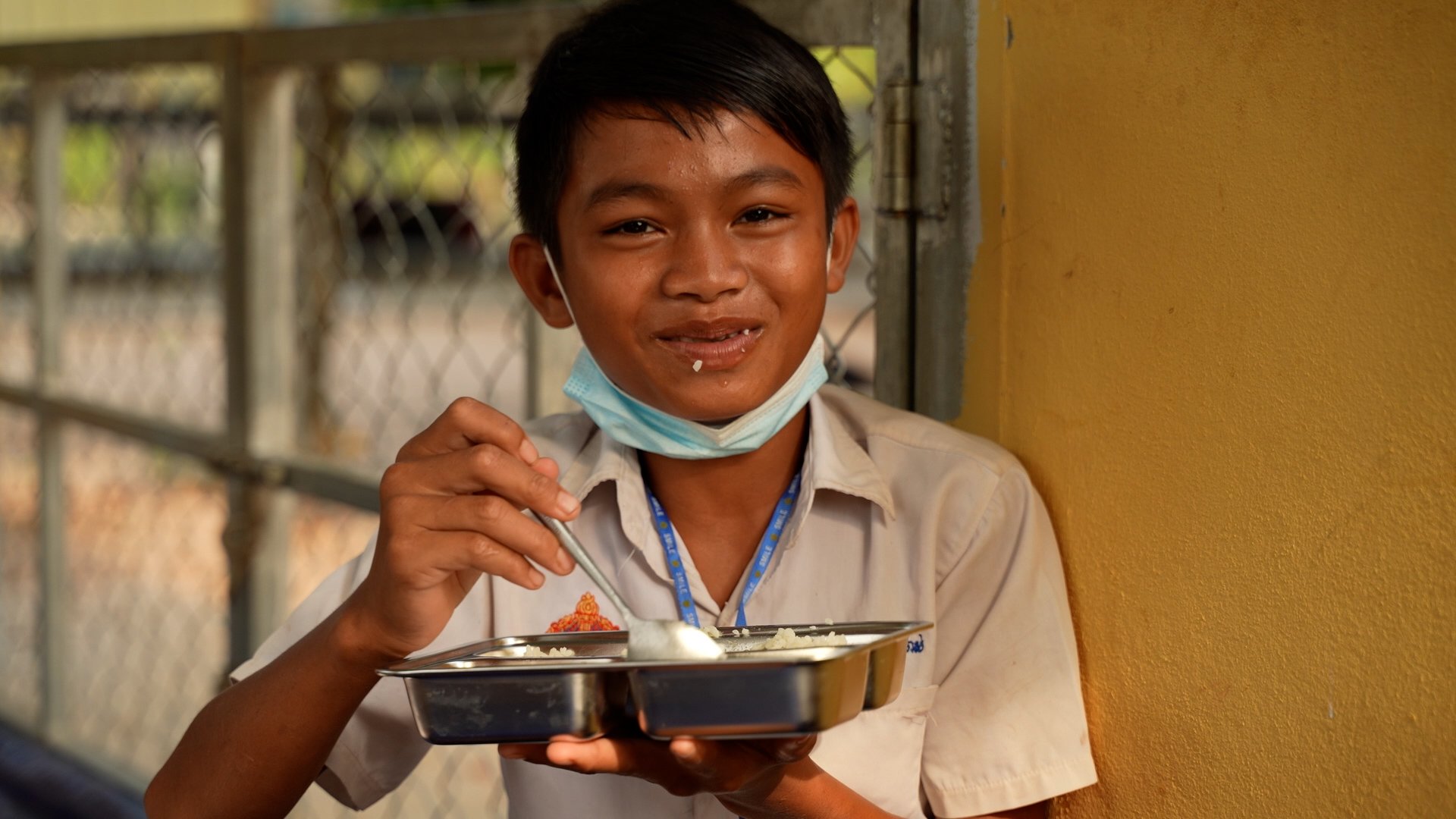 Boy smiles while eating rice