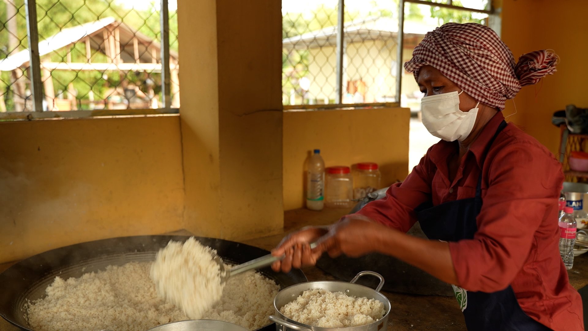 School cook puts rice into a bowl. Frame grab working as a cameraperson working for WFP Cambodia