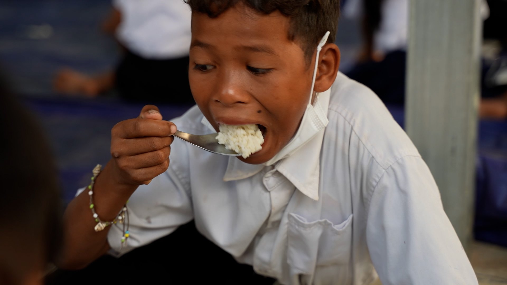 Boy puts a big spoon of rice into his hand