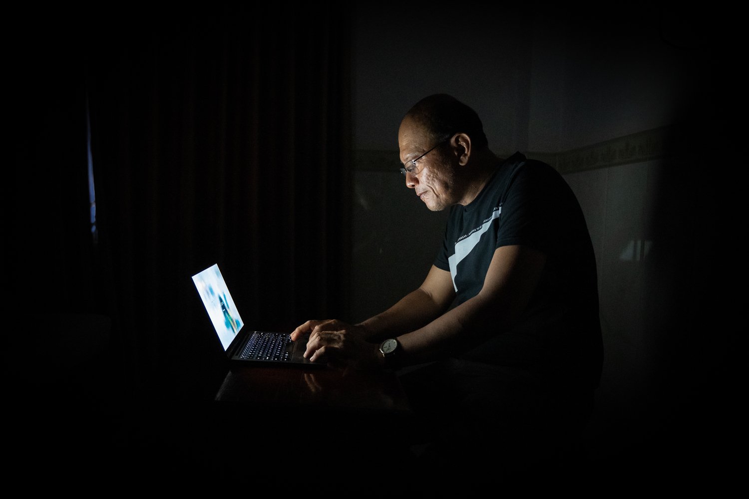 Sophal works on his masters on his computer late at night