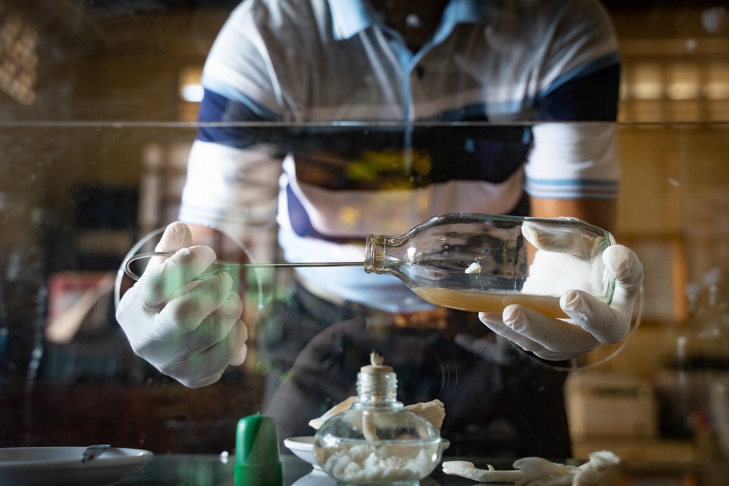 A close up of Nin Samreth’s hands as he puts a piece of mushroom in the mother-of-mushroom solution, ICC Office, Banlung.