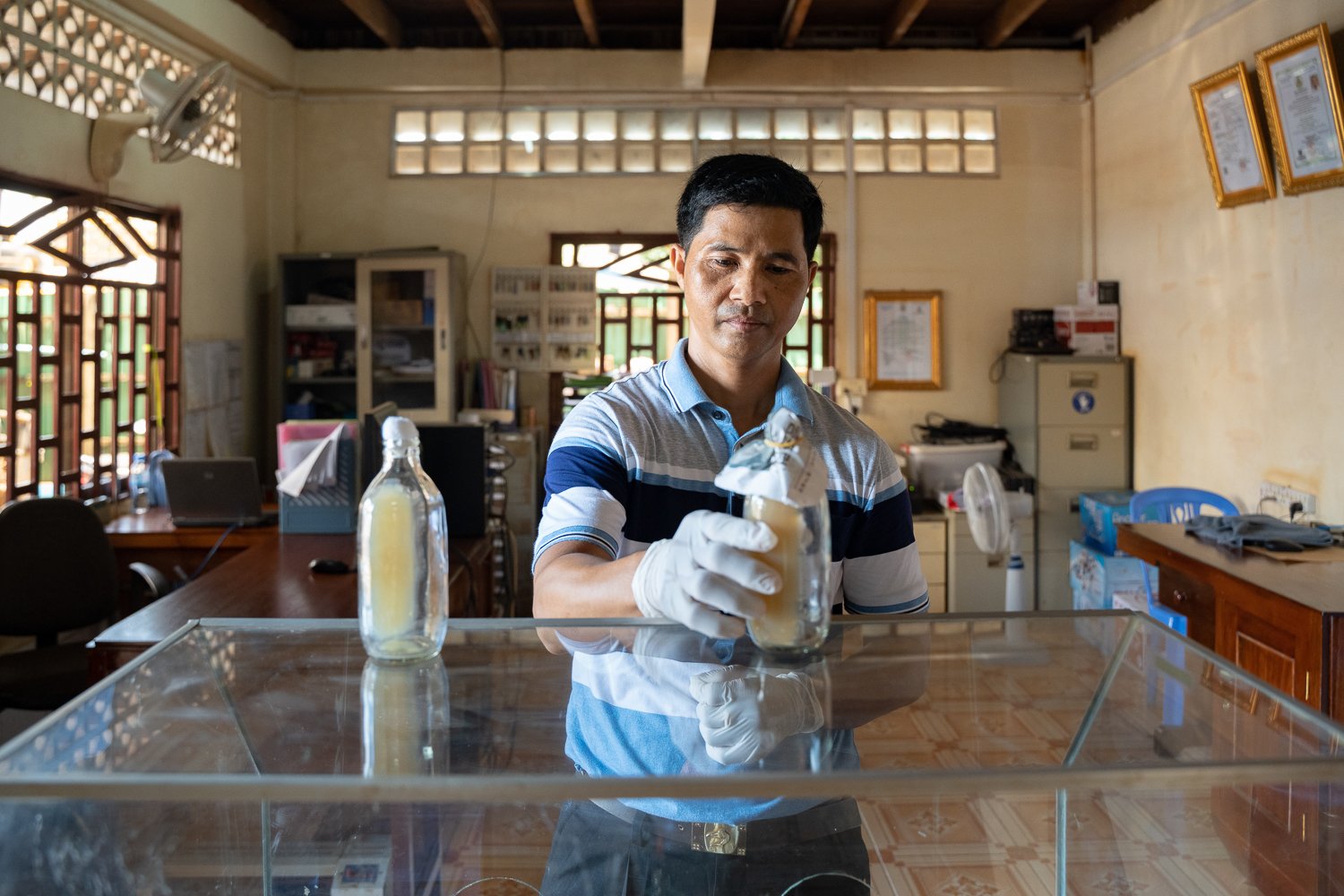 Nin Samreth places a bottle containing mother-of-mushroom solution on the top of the work surface as part of the mushroom production process