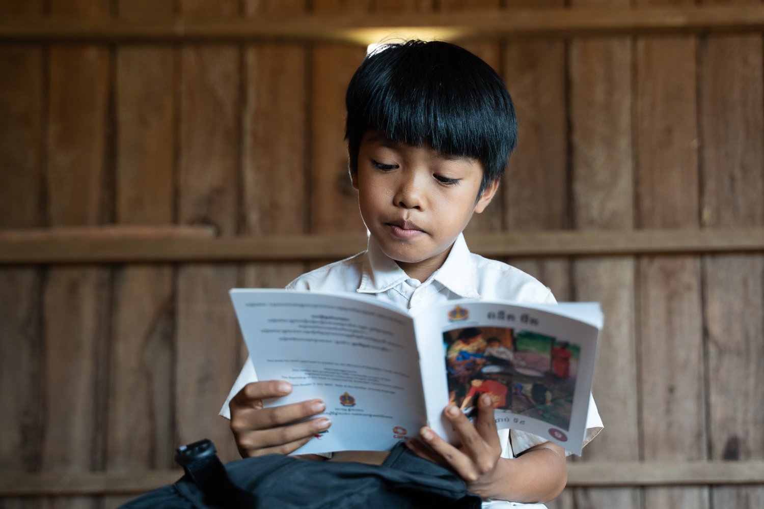 Vang Chiva sits at home reading a book in his indigenous language, Ratanikiri Province, Cambodia