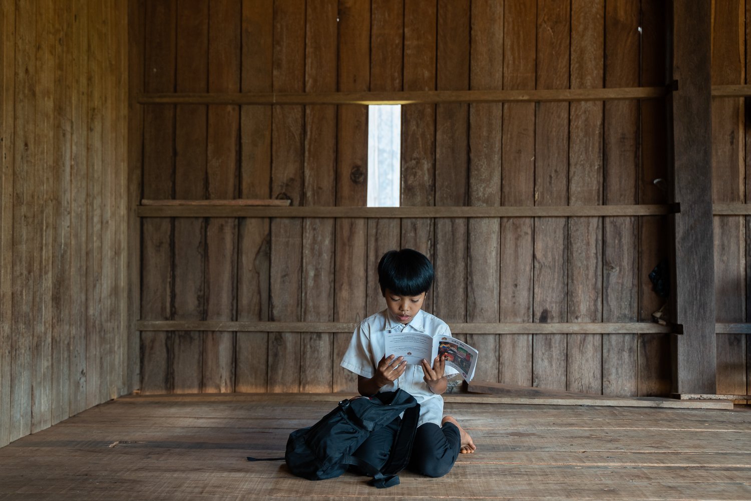 Vang Chiva sits at home reading a book in his indigenous language, Ratanikiri Province, Cambodia