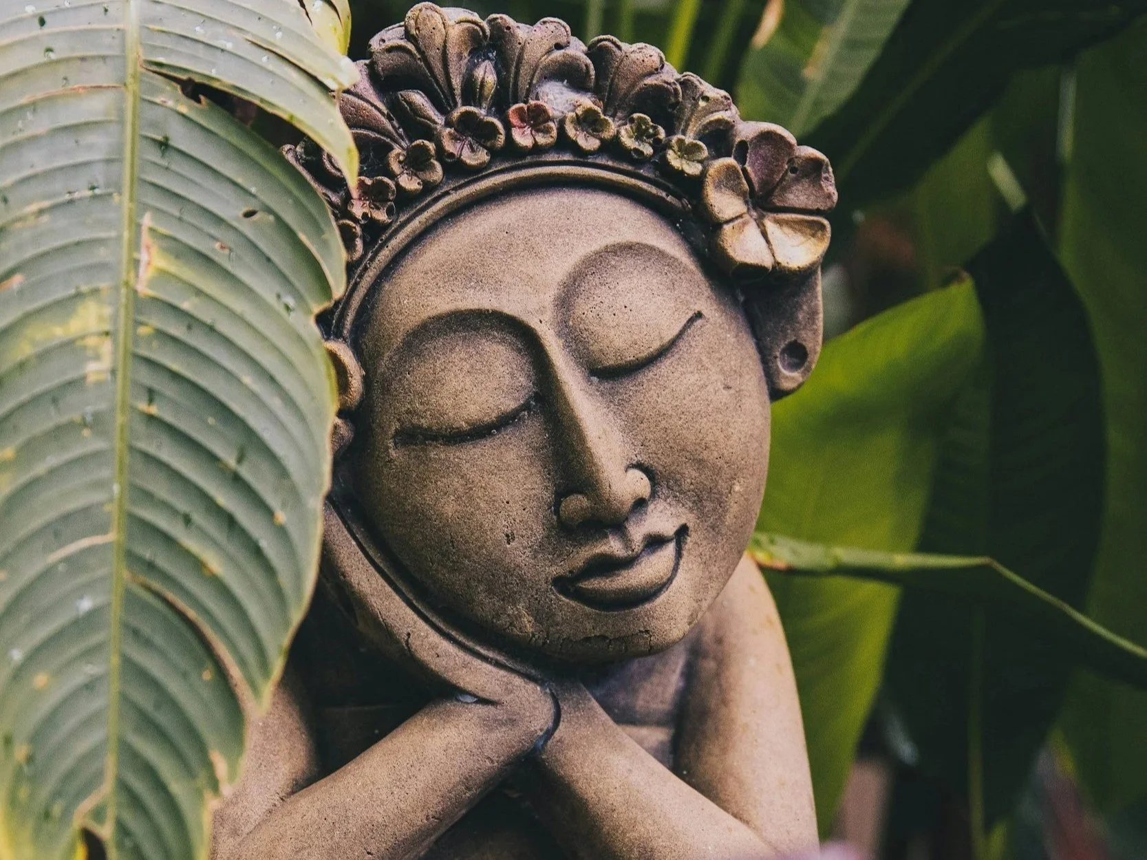 Traditional Thai Buddha statue surrounded by tropical foliage representing Thai massage training in Cleveland Ohio