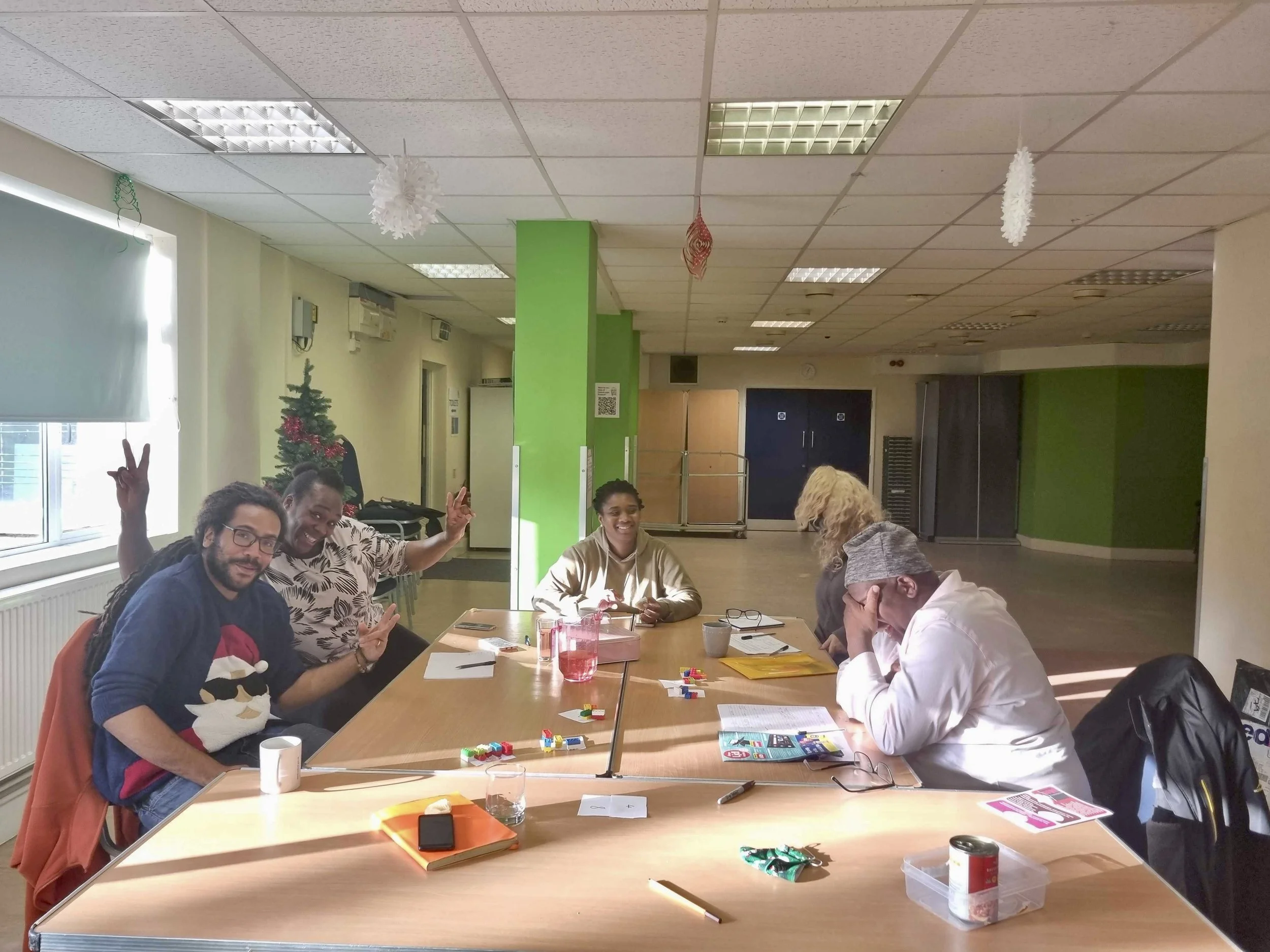 A group of people sitting round a table with lego blocks and notebooks