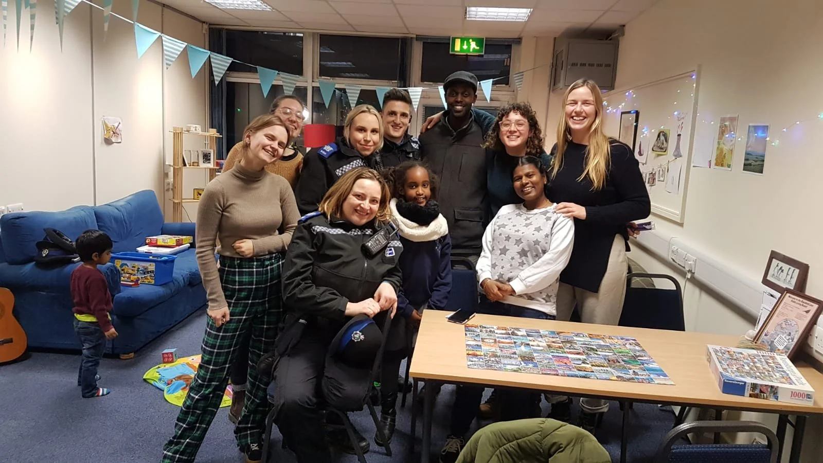 A group of residents and police officers standing around a jigsaw in a community living room
