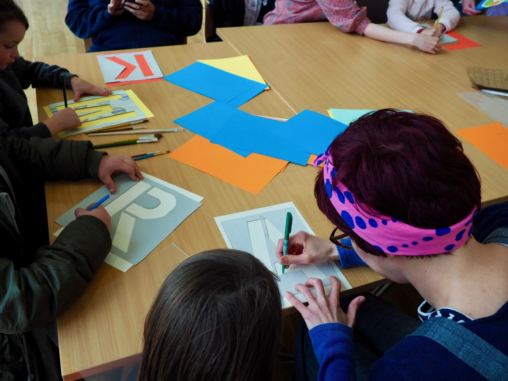a Big Sibling helping their Little Sibling stencil a letter