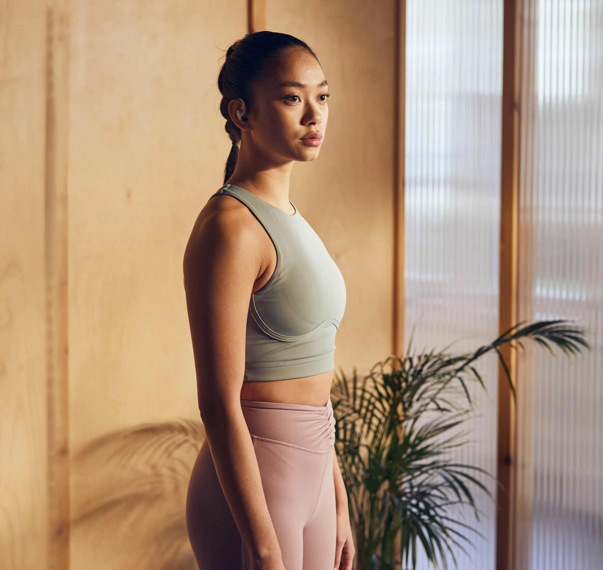 A women wearing sport clothing starts a workout class wearing in ear headphones in this advertising image by photographer Jon Enoch
