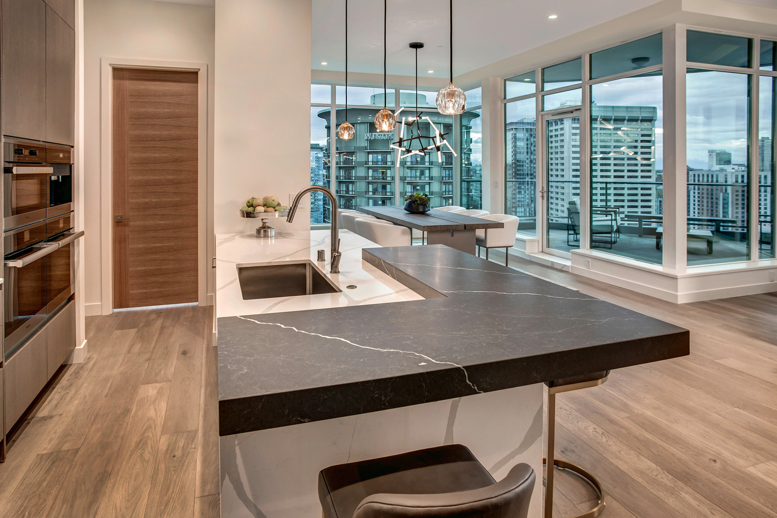 Calacatta Quartz countertops with an accent Sorano honed Quartz countertop and Boule De Cristal Restoration Hardware Modern pendants.