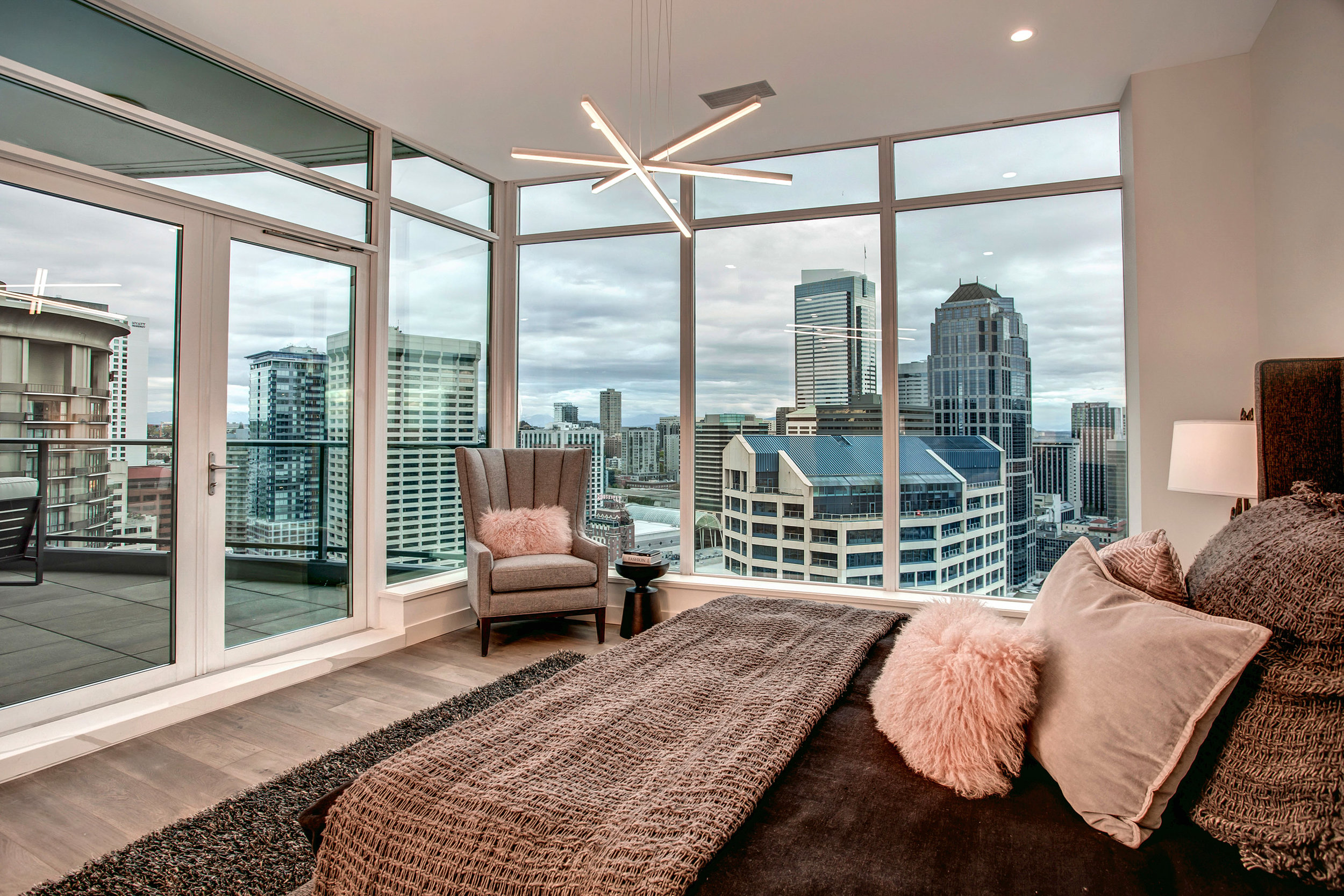 Master suite with floor to ceiling windows, dramatic city views, and access to the covered balcony.