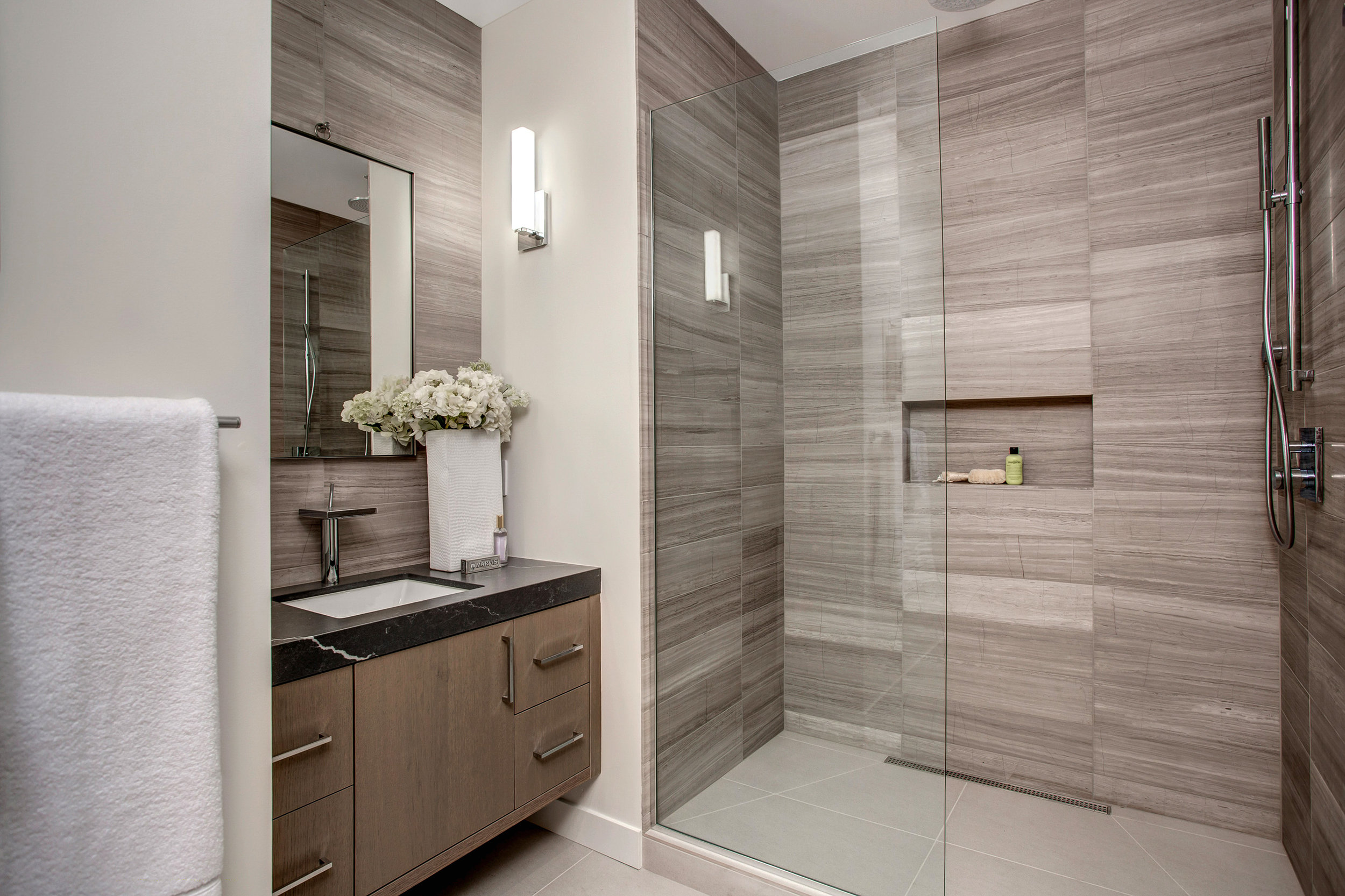 En suite guest bathroom with floor to ceiling Marble tile shower and vanity wall.