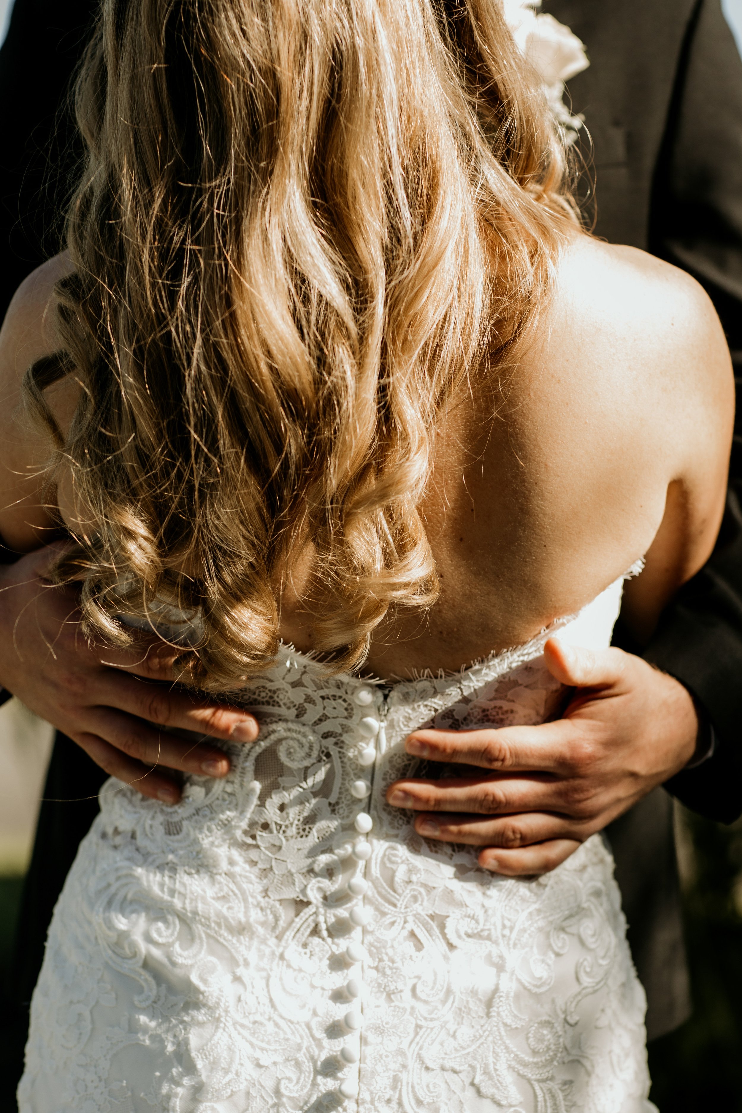 Back of the bride's dress, with her husband's hands around her