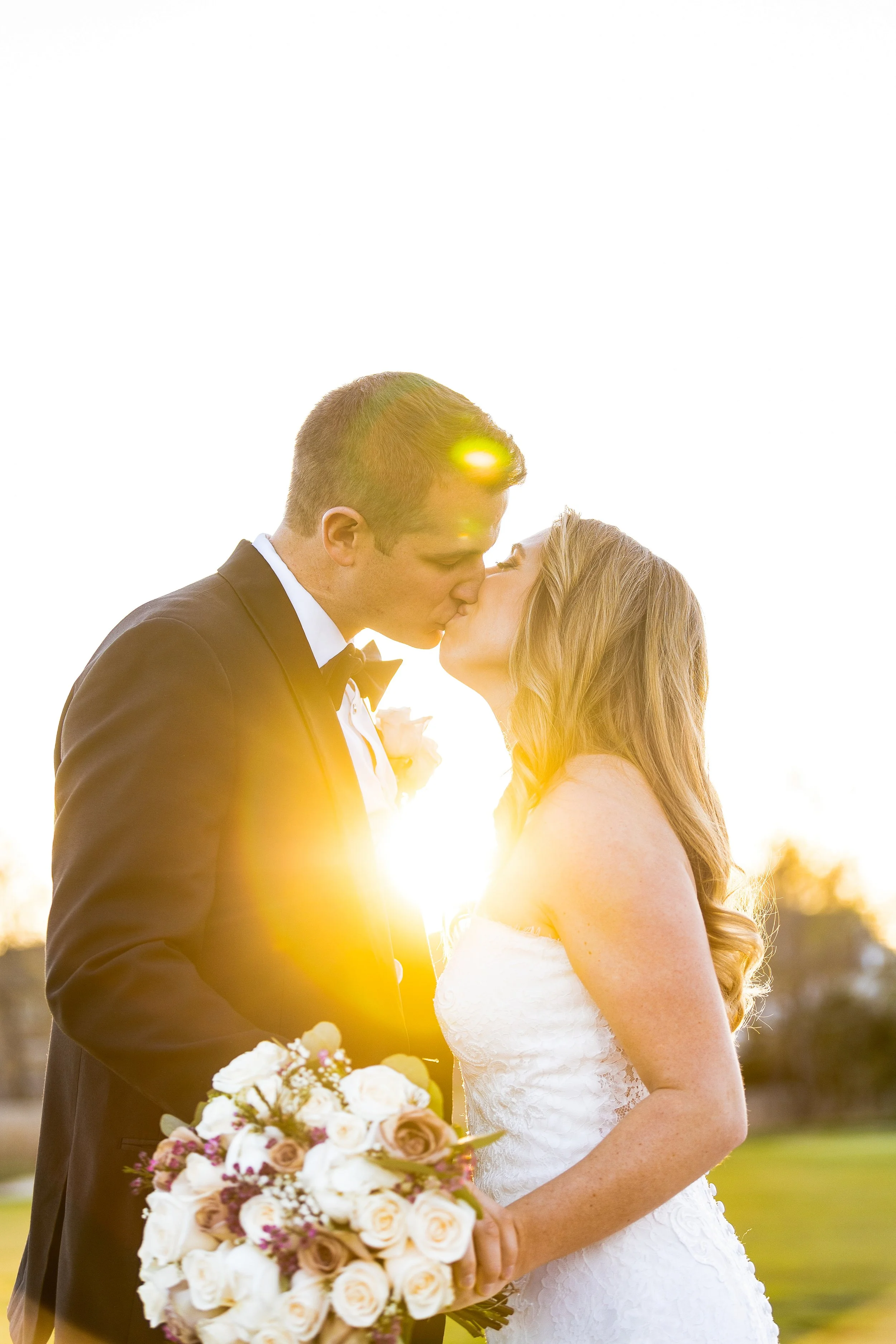 Bride holding bouquet and kissing her groom