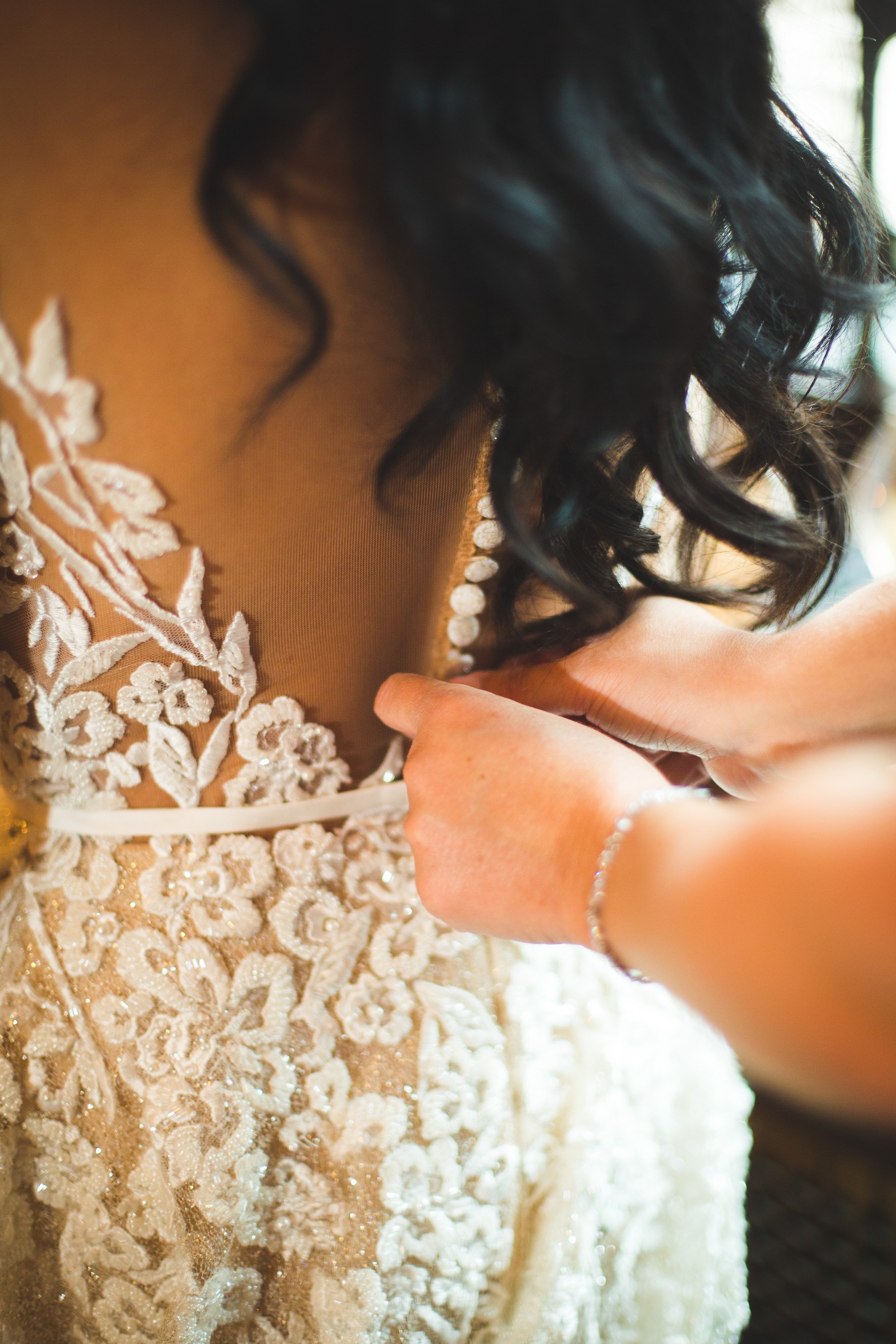 Bride having her gown buttoned up
