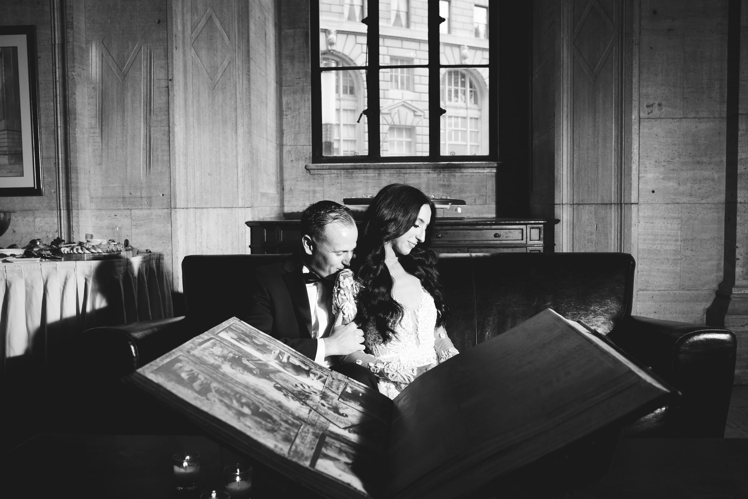 Groom kissing brides shoulder while sitting on a couch