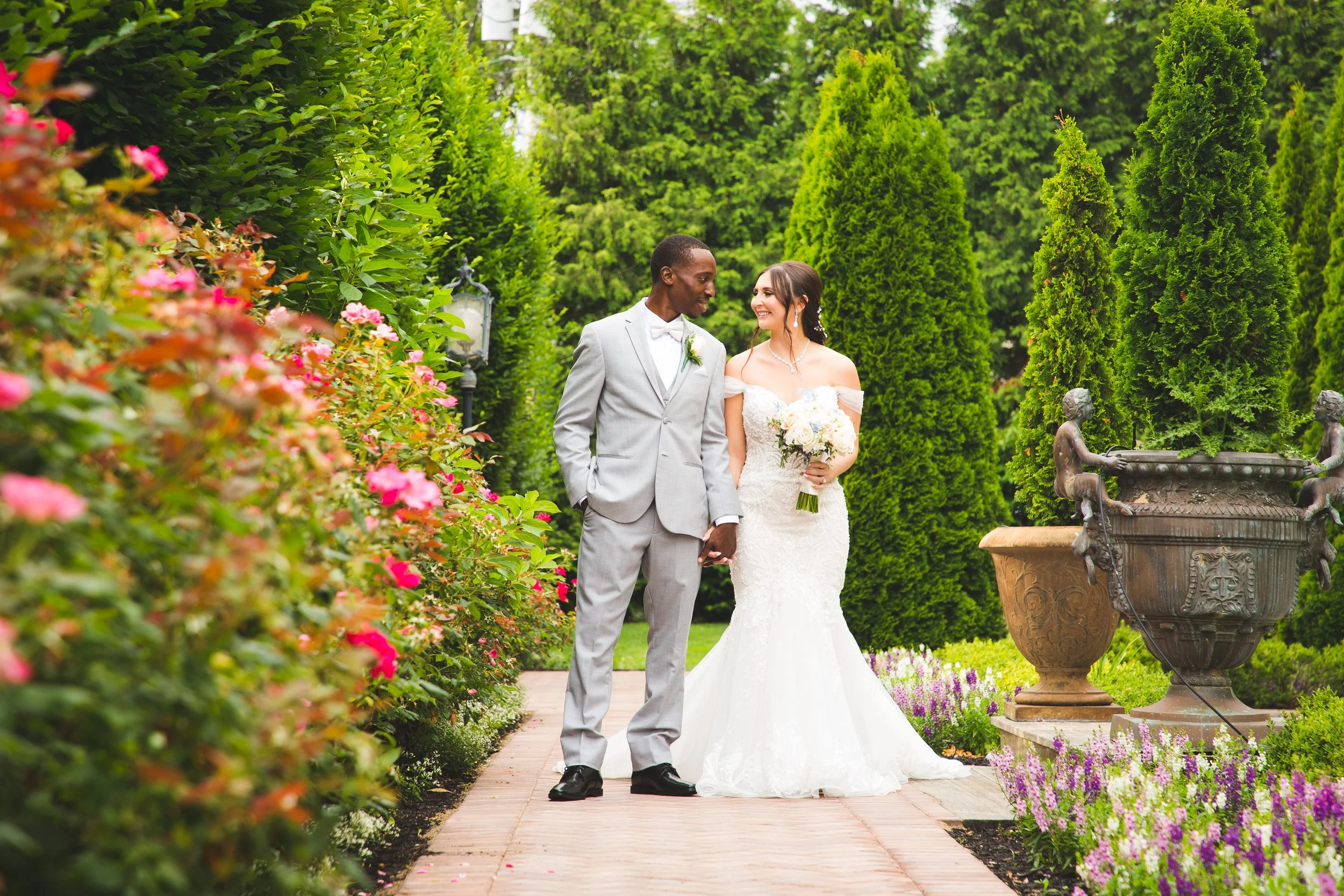 Husband and wife walking hand in hand through the garden on their wedding day
