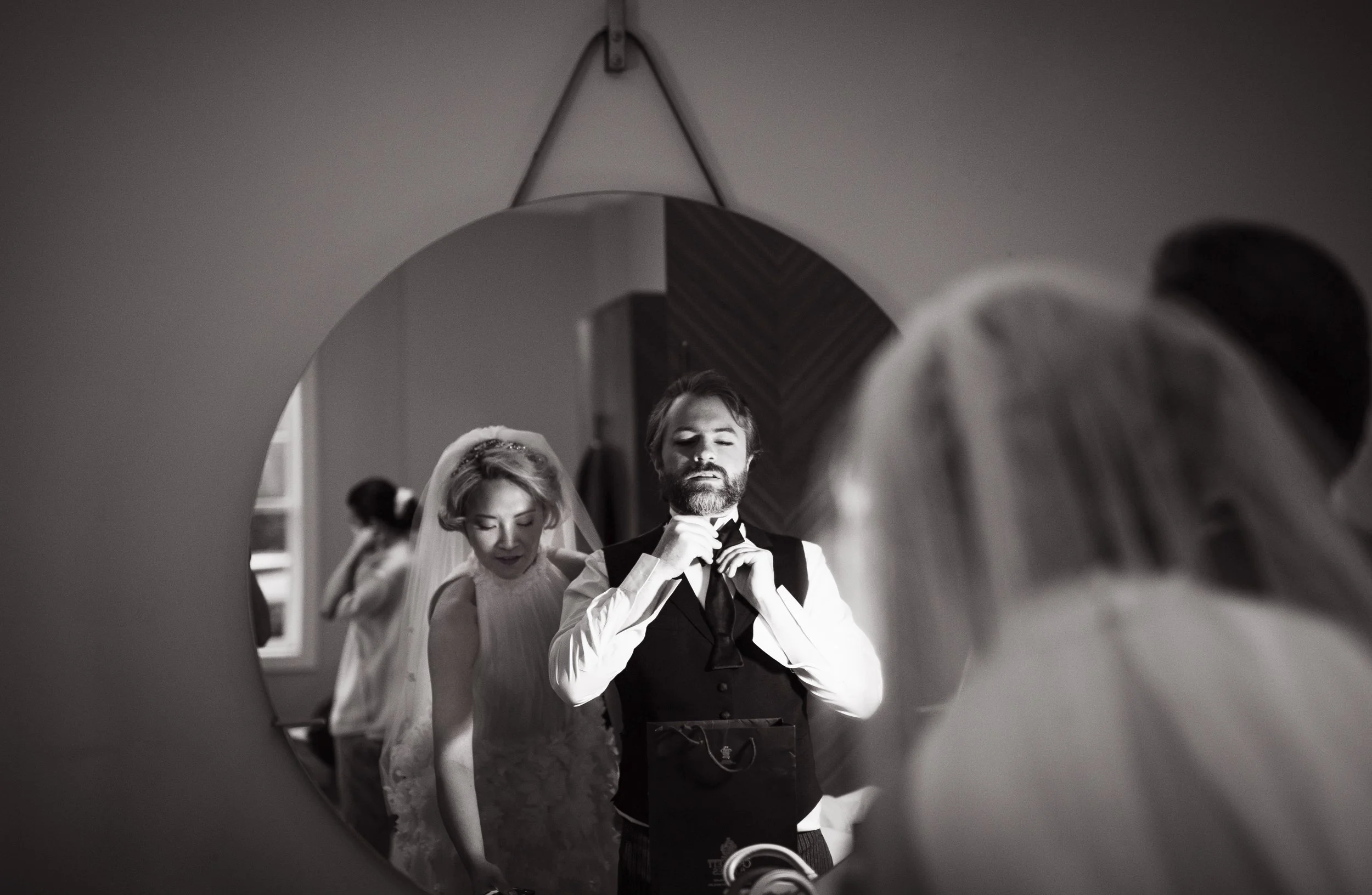 Bride and groom looking at their reflection in a round mirror getting ready for their wedding ceremony together
