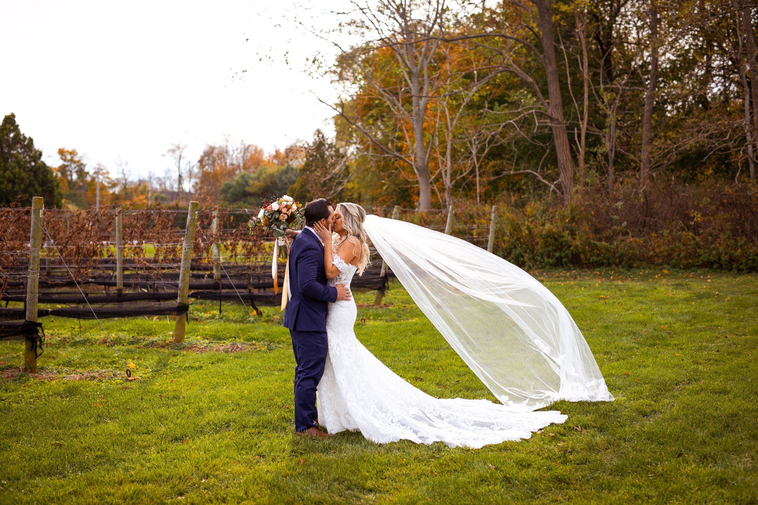 Bride and groom kissing during their first look outside in front of a vineyard in the fall