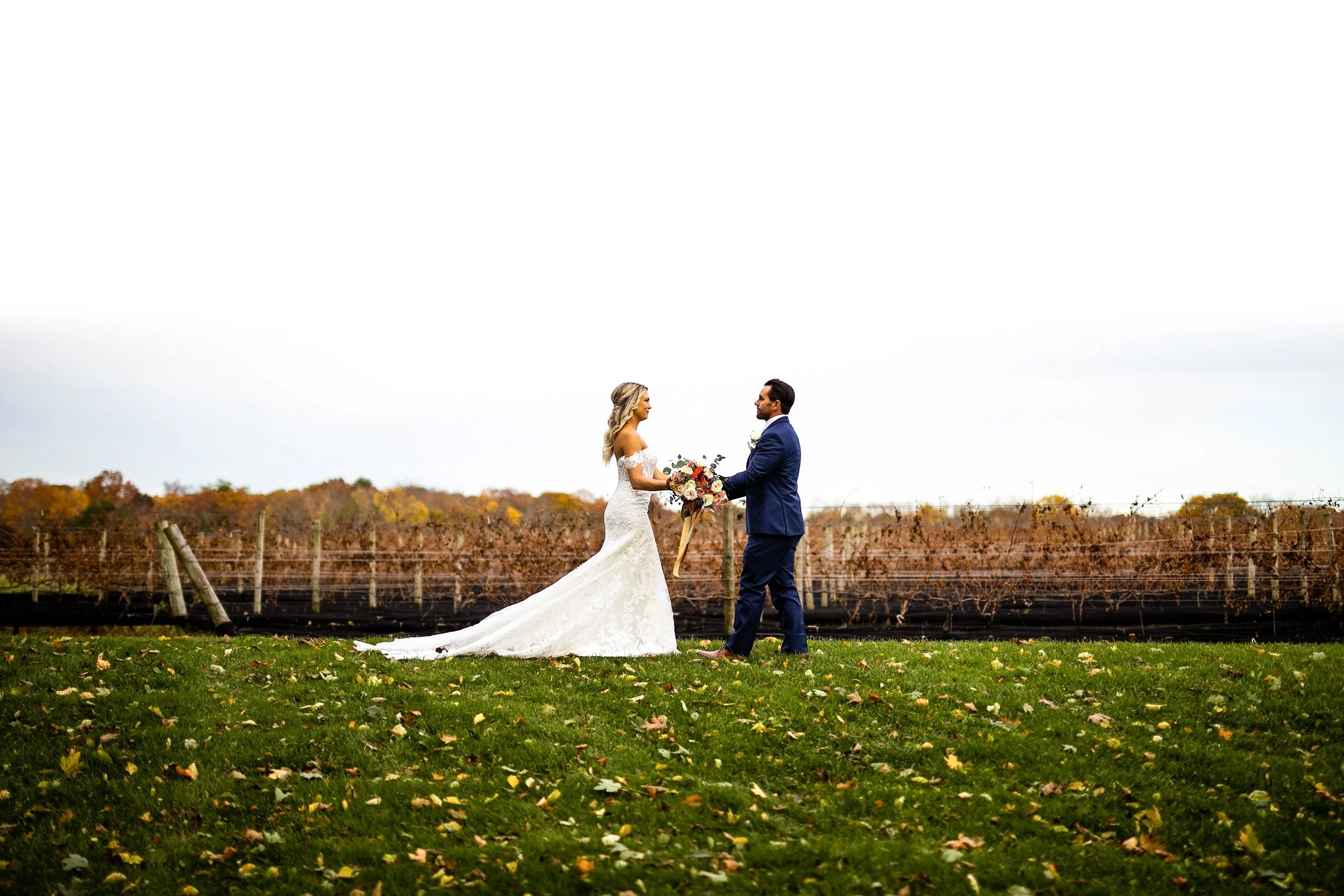 Bride and groom walking toward each other in front of a vineyard on long island during the fall