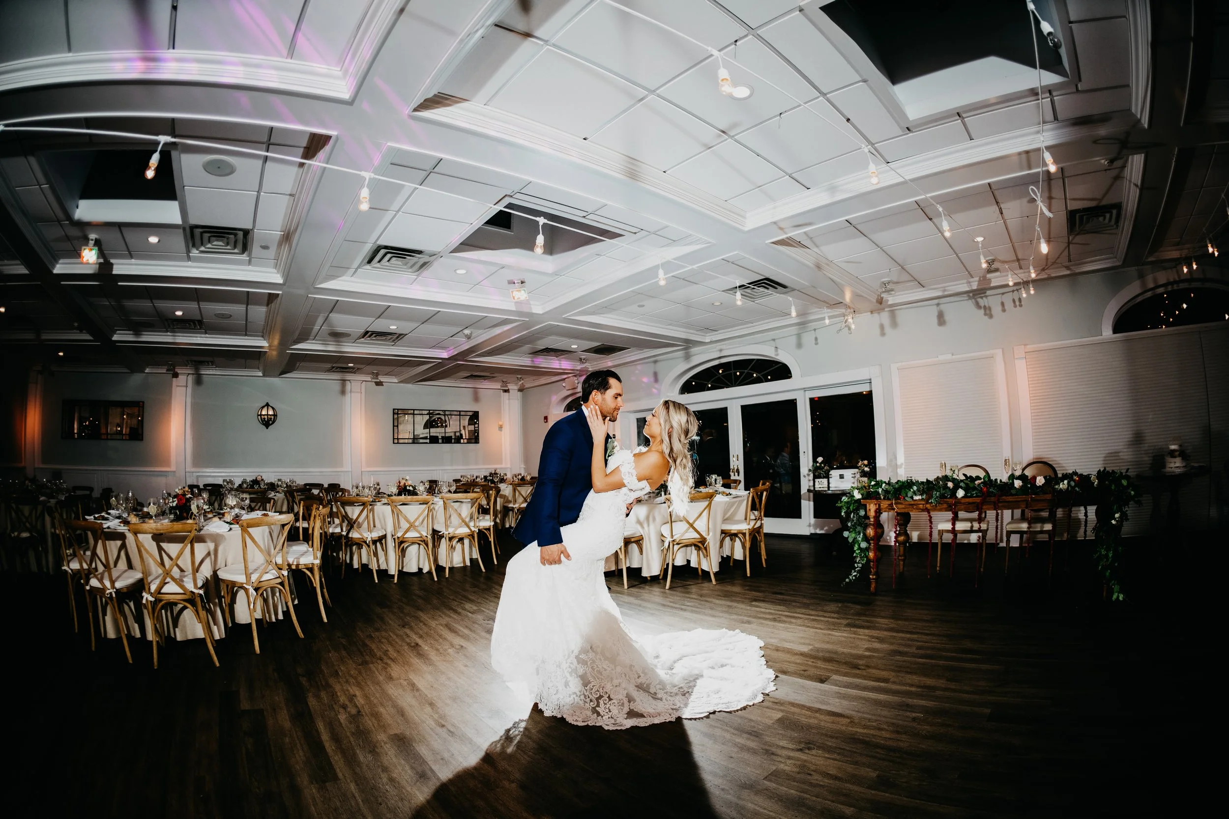 Groom dipping his wife in their wedding reception venue's ballroom