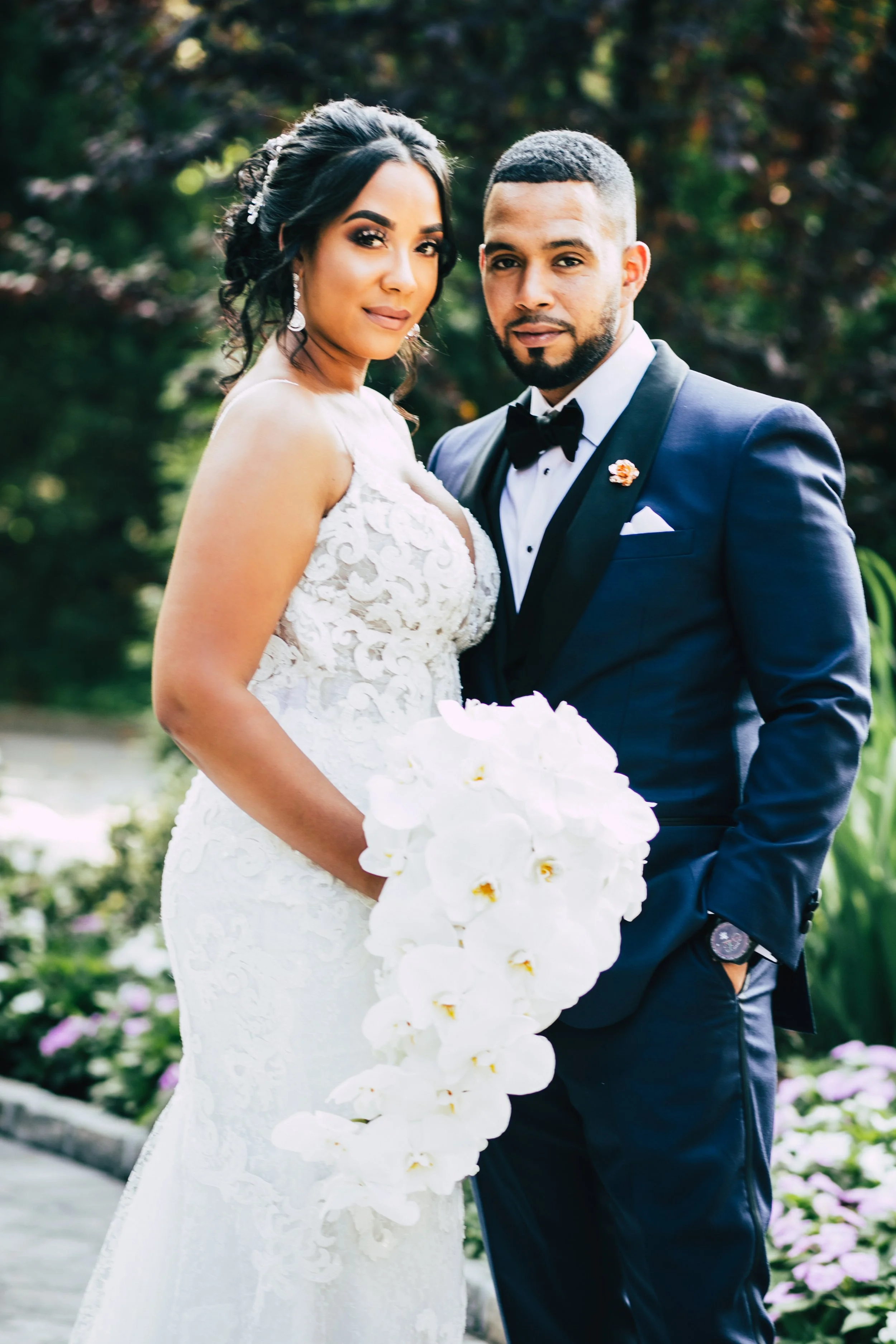 Bride and groom in a garden looking dramatically at camera
