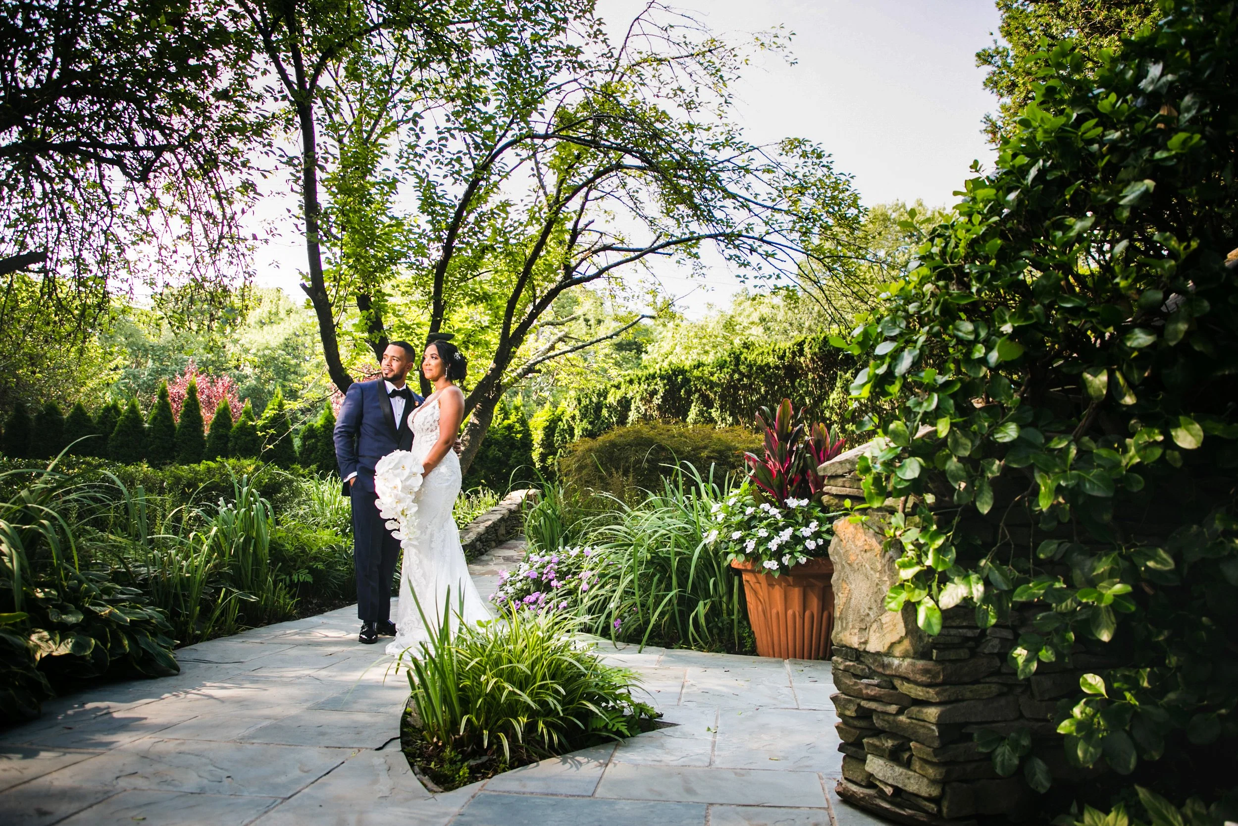 Bride and groom looking into distance in the midst of a garden at their long island wedding venue