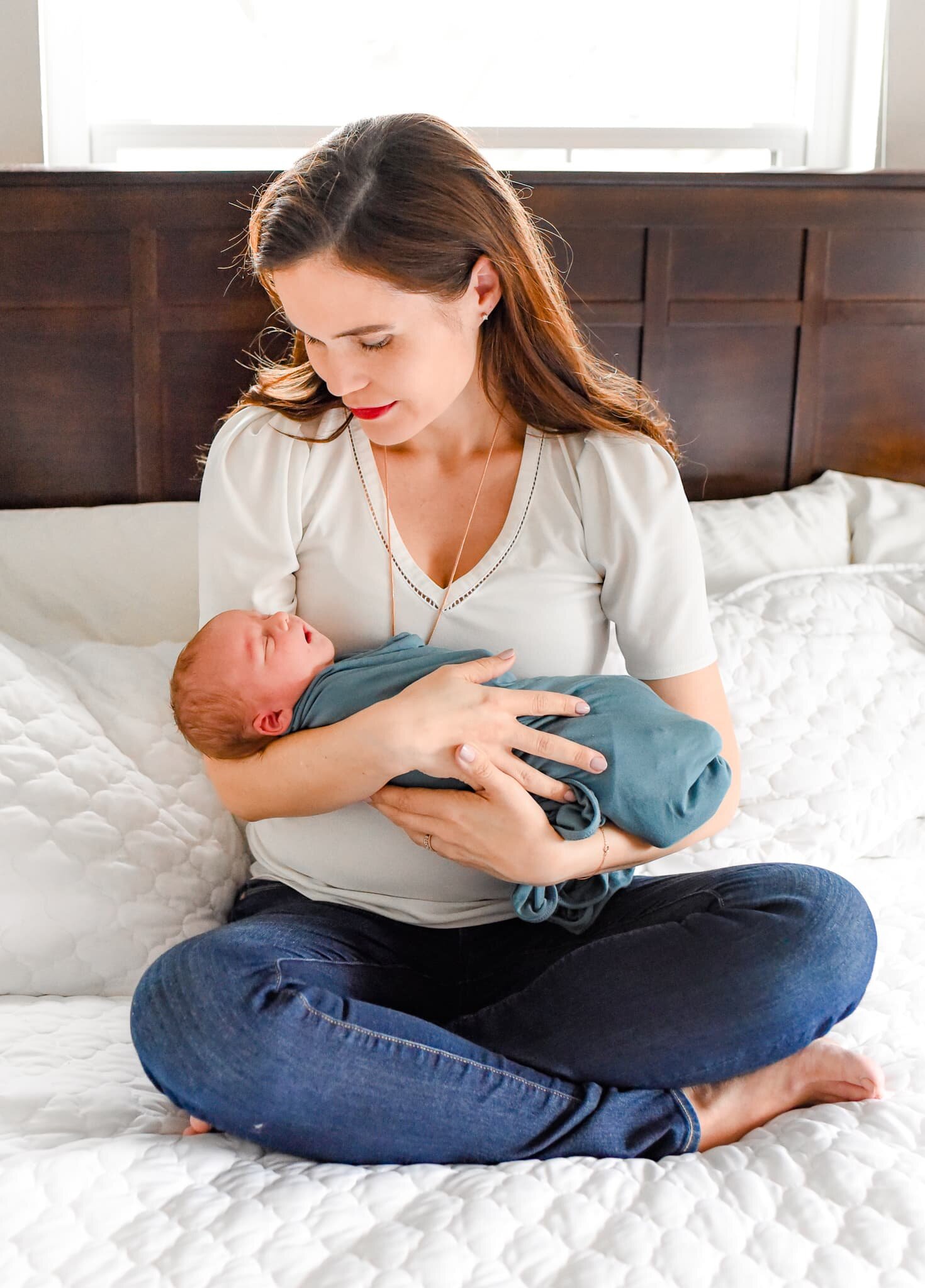 Silver Spring Maryland Newborn Photoshoot - mom cradling baby on bed