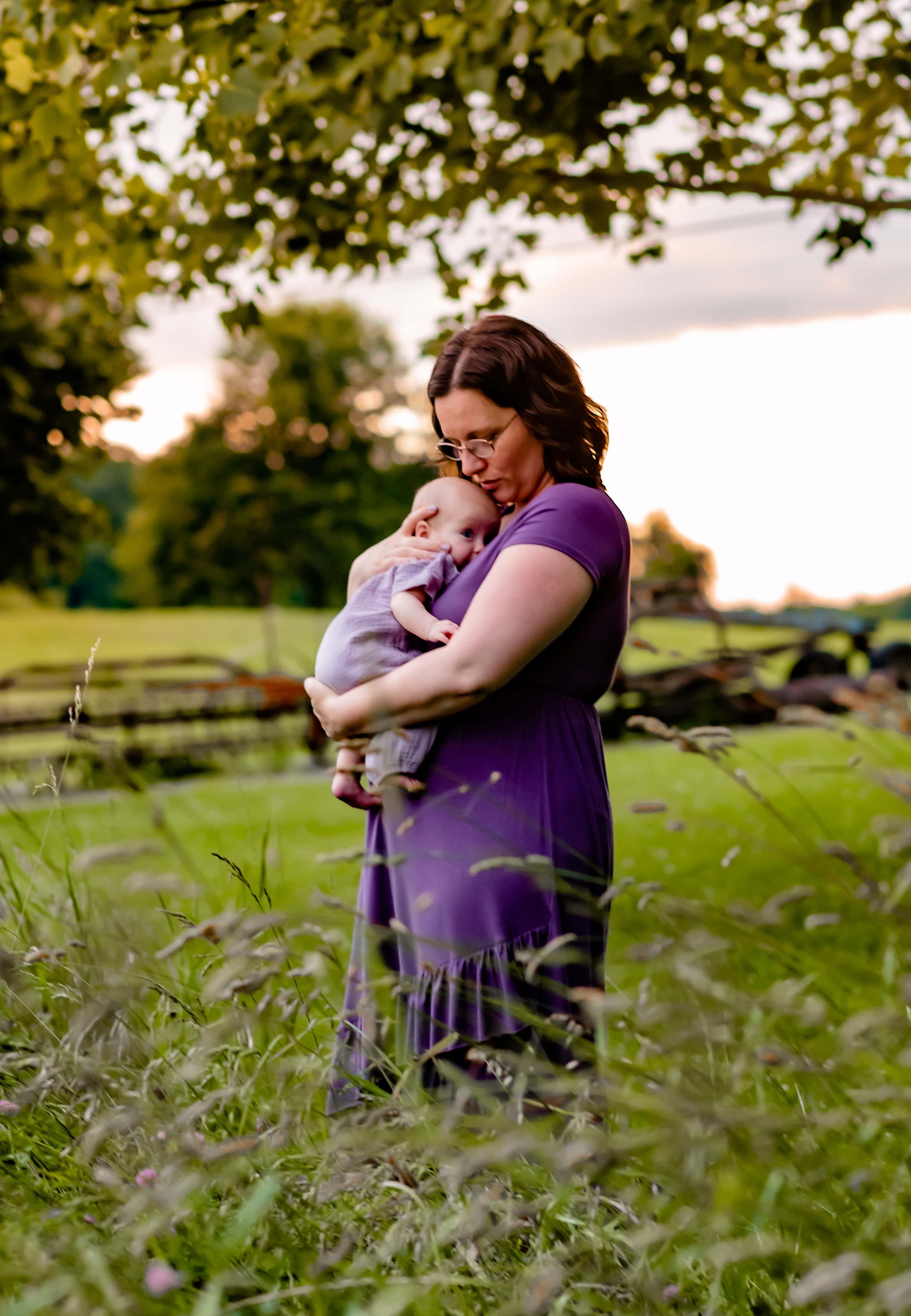 Maryland Newborn Photographer mom cradling baby in field