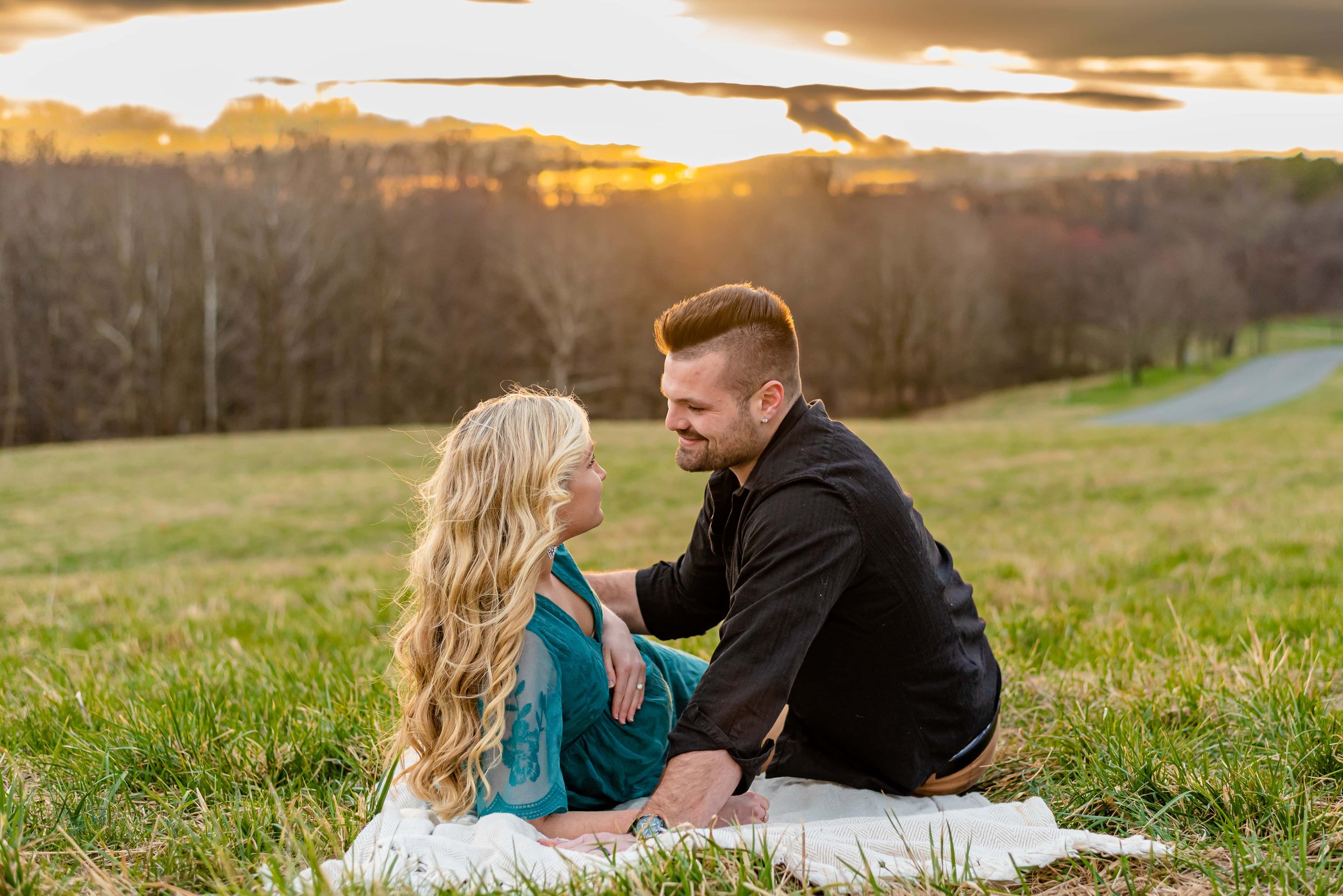 Maternity photos with couple laying on a blanket in a field