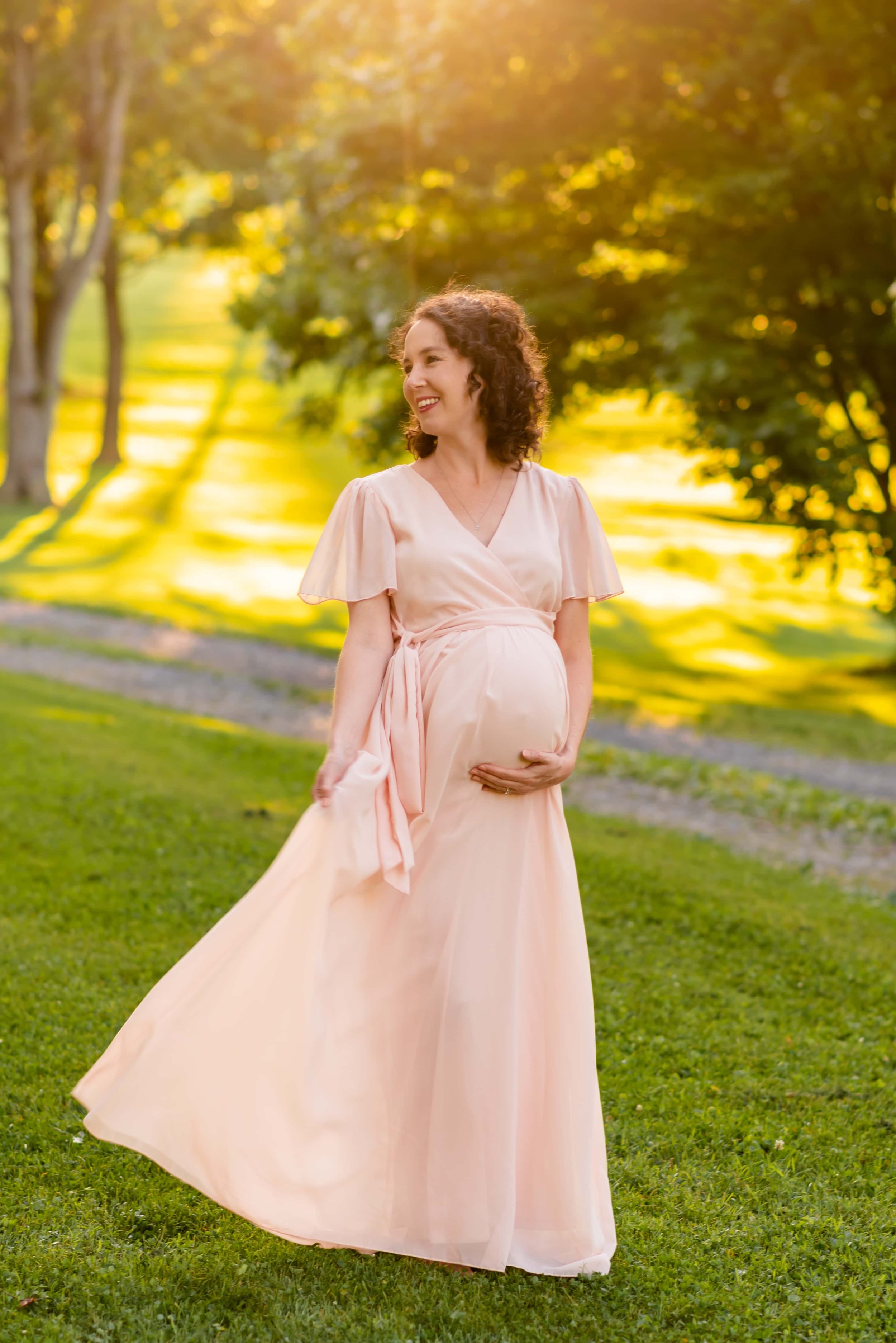Maryland Maternity Photo of Woman Holding Her Belly and Playing with Her Dress