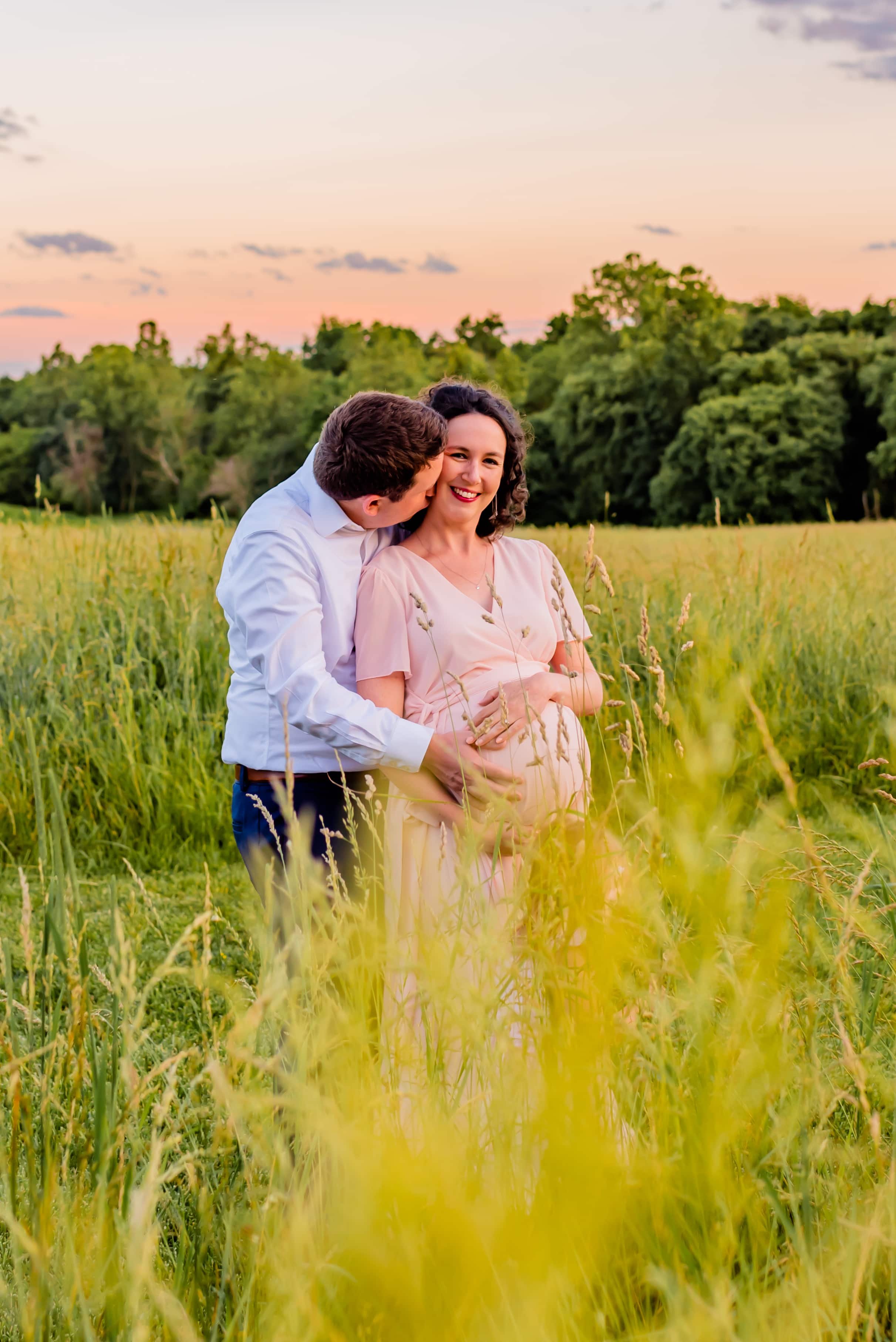 Maternity photo of man and pregnant woman standing in a field 