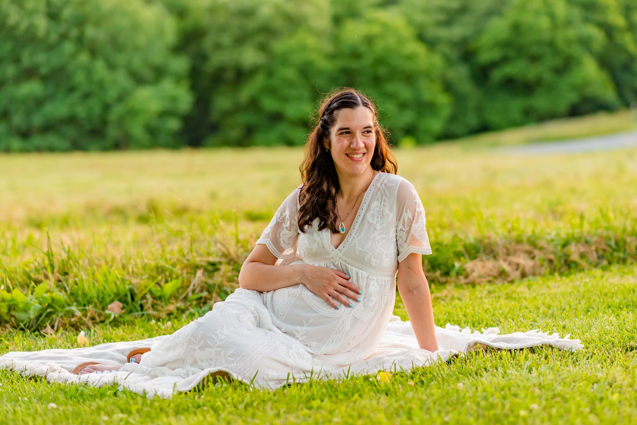 Maryland Maternity photoshoot of pregnant woman sitting on blanket holding her belly