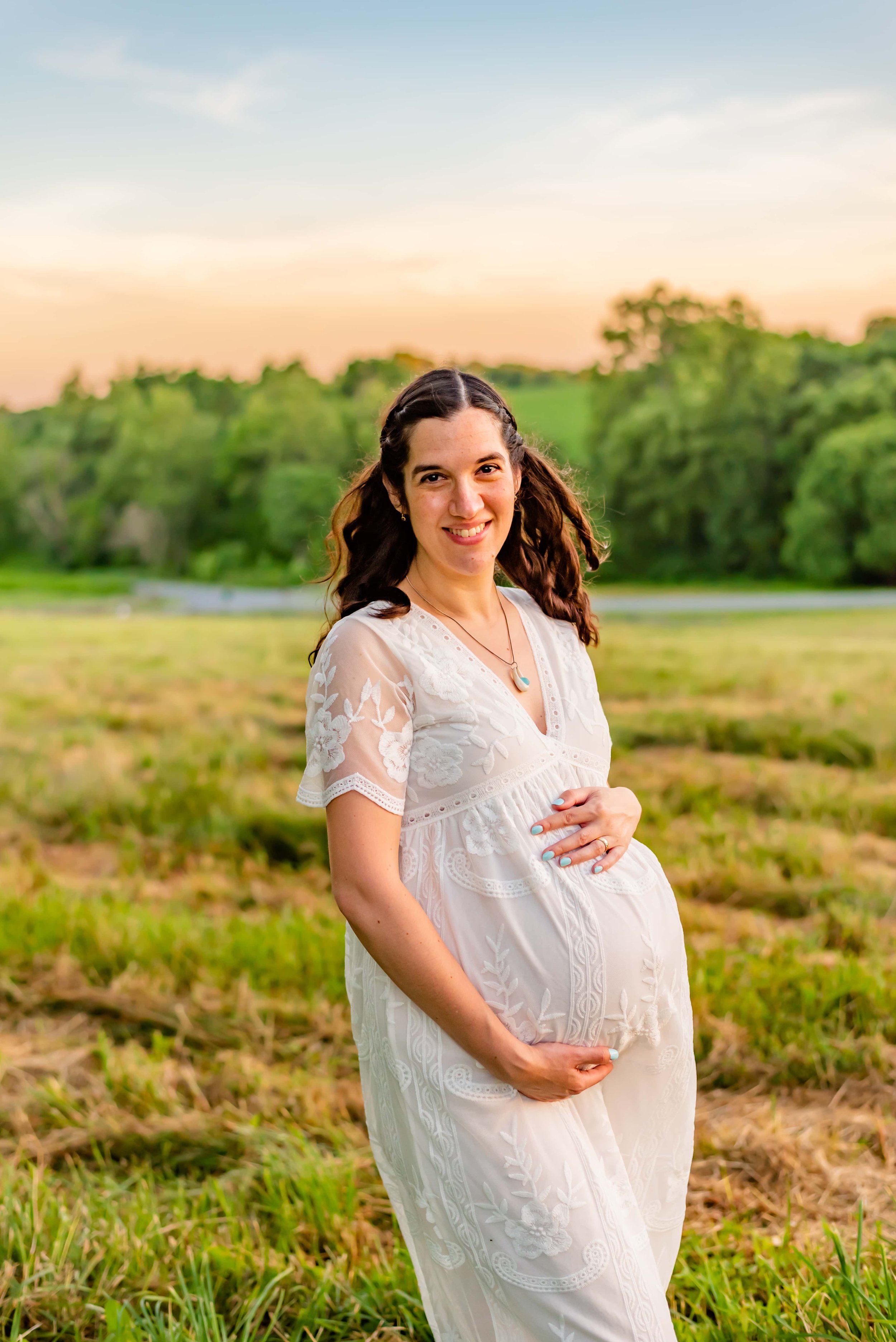 Maternity photo of woman in Maryland standing in a field smiling at the camera