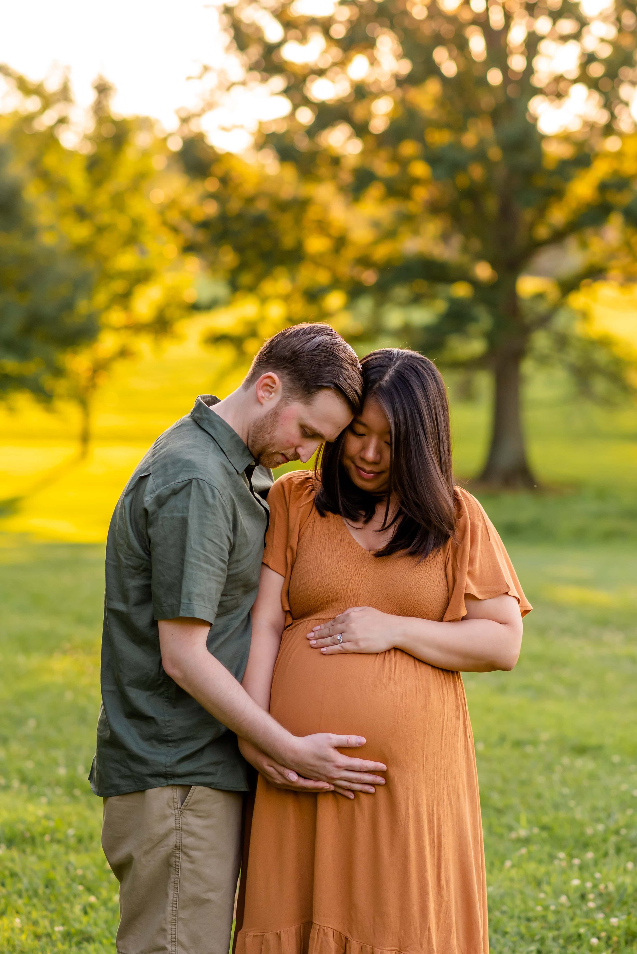 Maryland summer maternity photo of couple at sunset looking at her belly