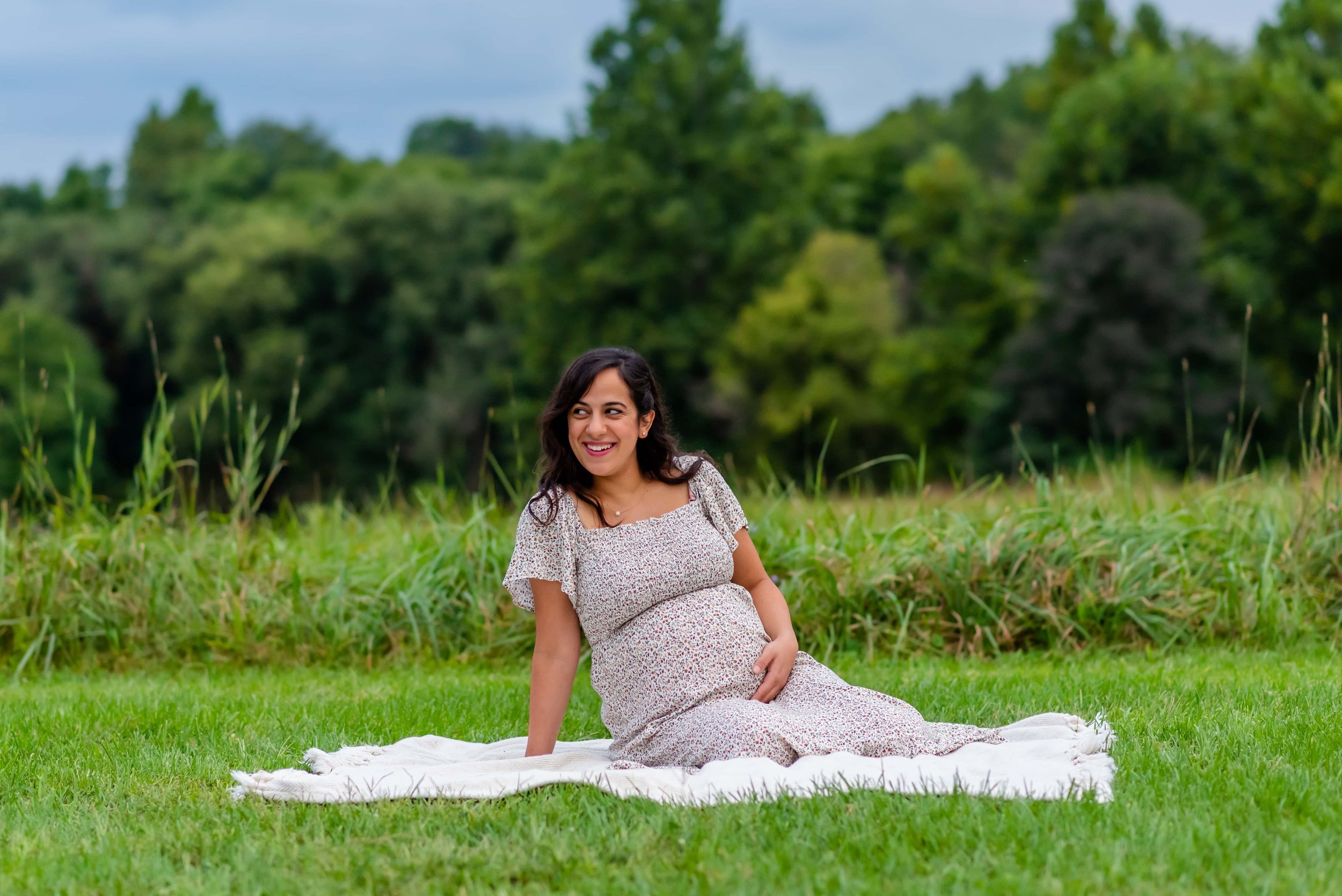 Maryland Maternity photo of woman sitting on a blanket smiling over her shoulder