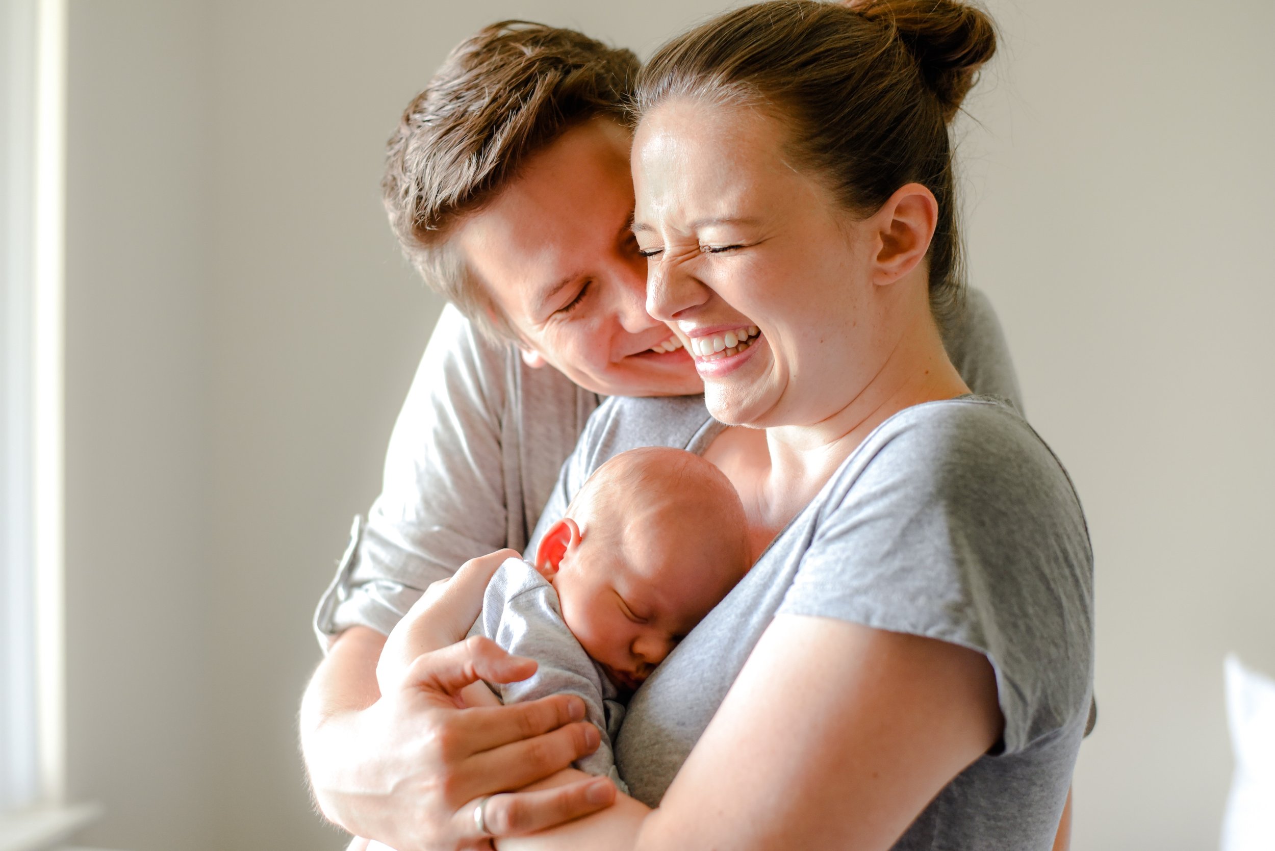 Natural newborn photograph of mom, dad and baby snuggling