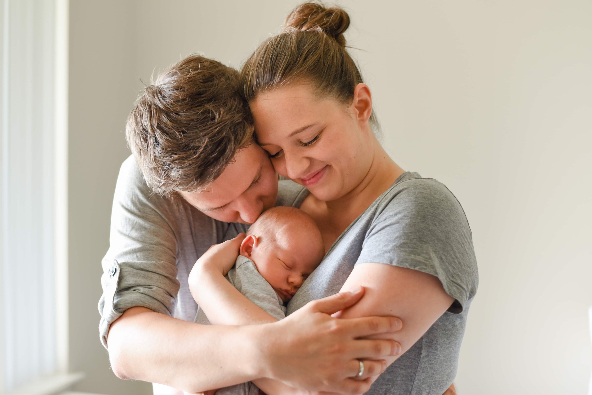 Natural newborn photograph of mom, dad and baby hugging