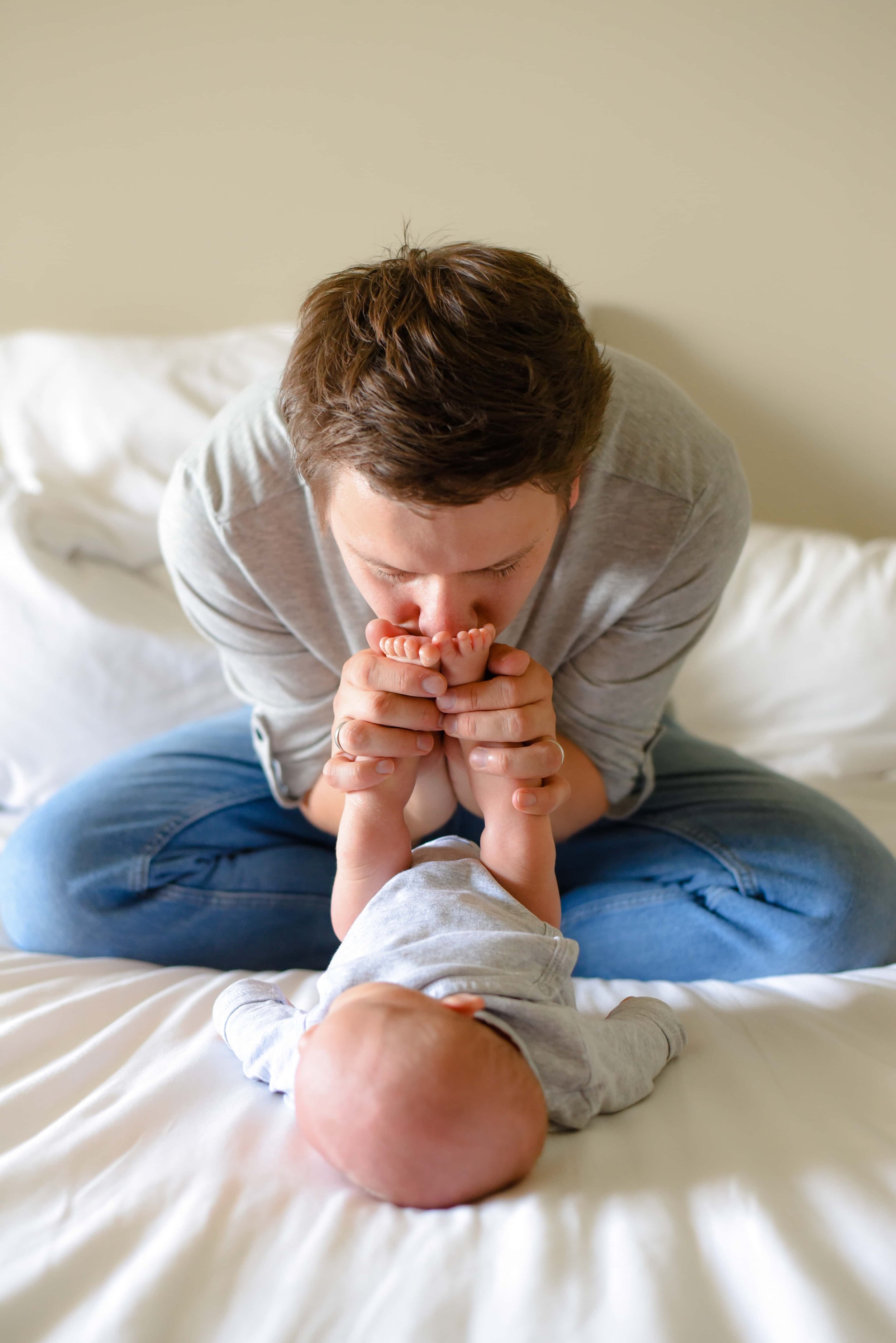 Natural newborn photograph of dad playing with the baby on a bed 