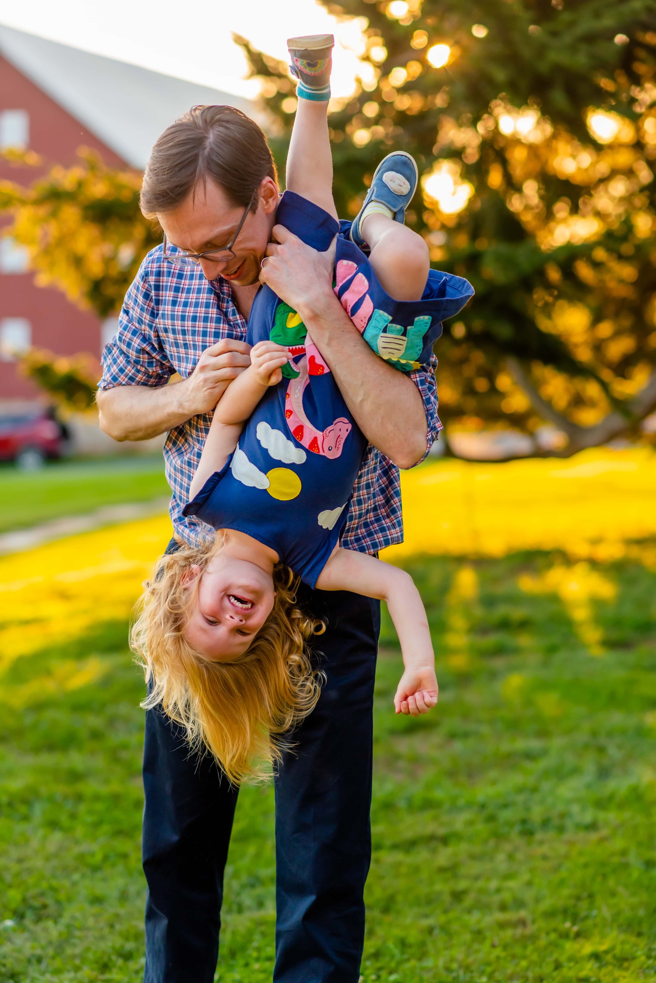 Summer family photo of dad holding daughter upside down