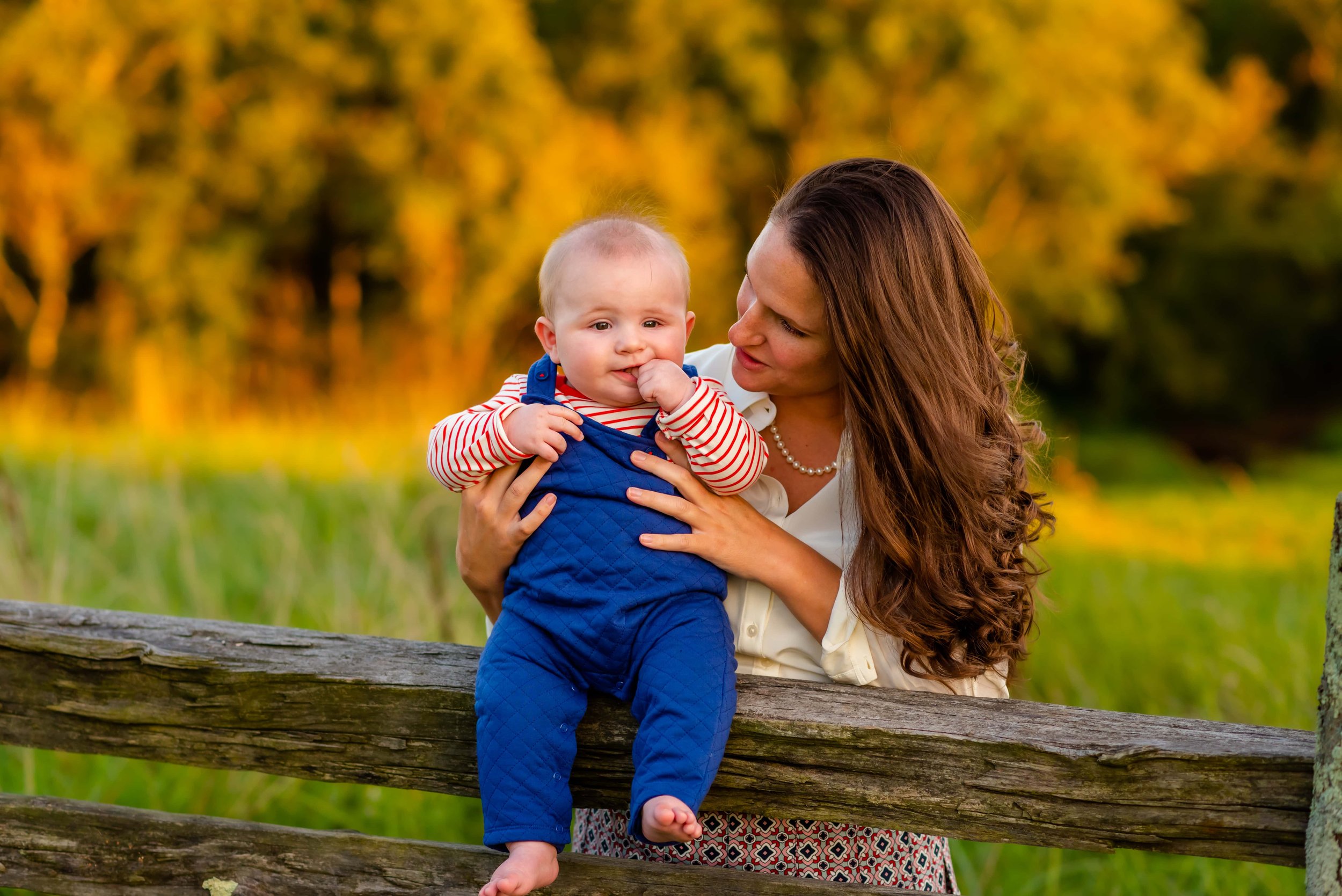 Summer family photo of mom holding baby on a fence