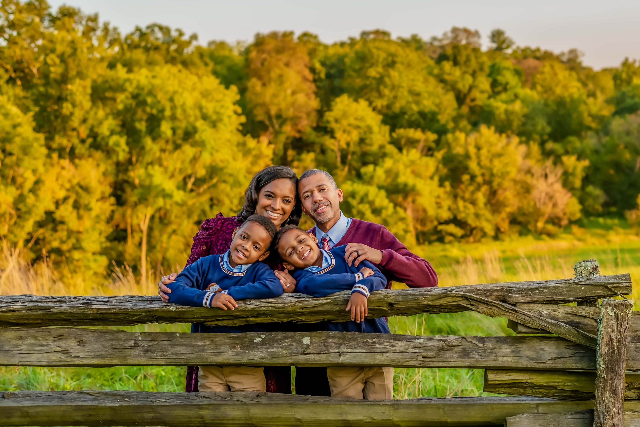 Fall family photo of family leaning on a fence