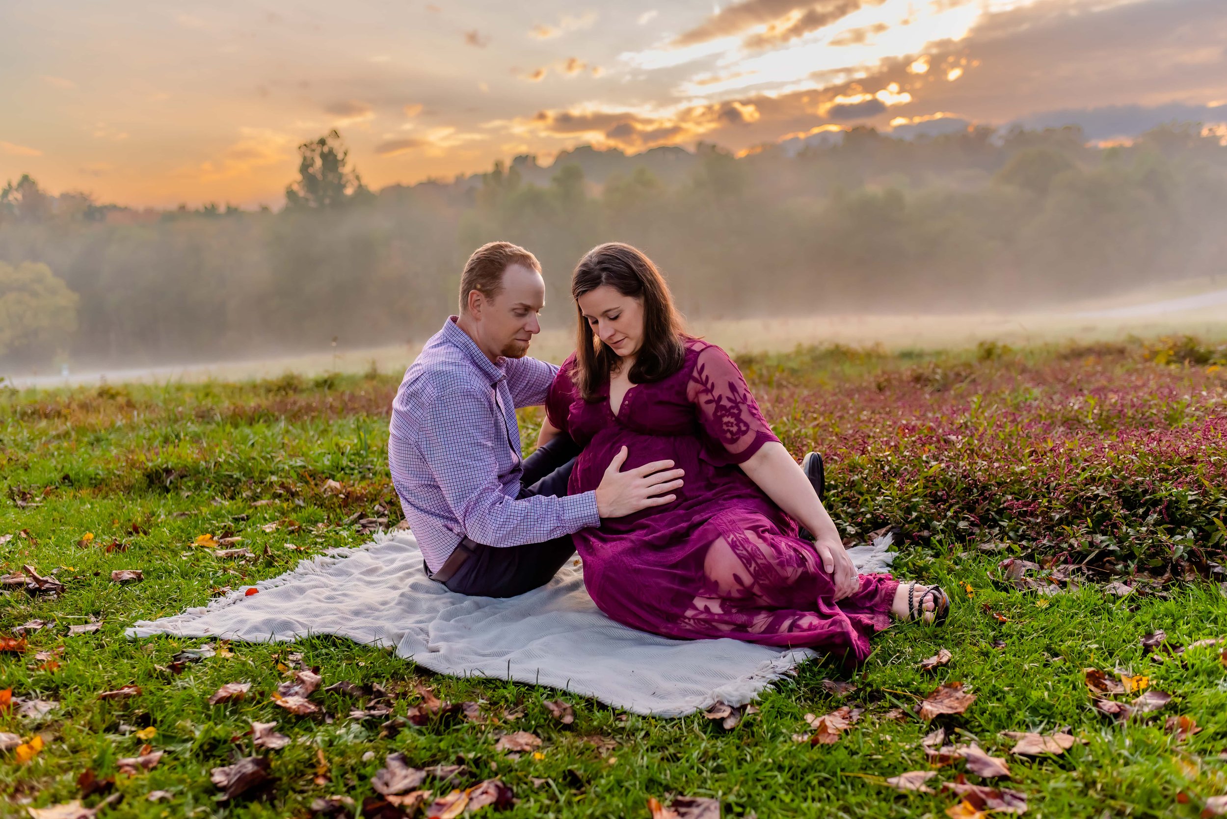Maryland Maternity Photos - Husband and Wife Sitting in a Field Looking down at her belly 