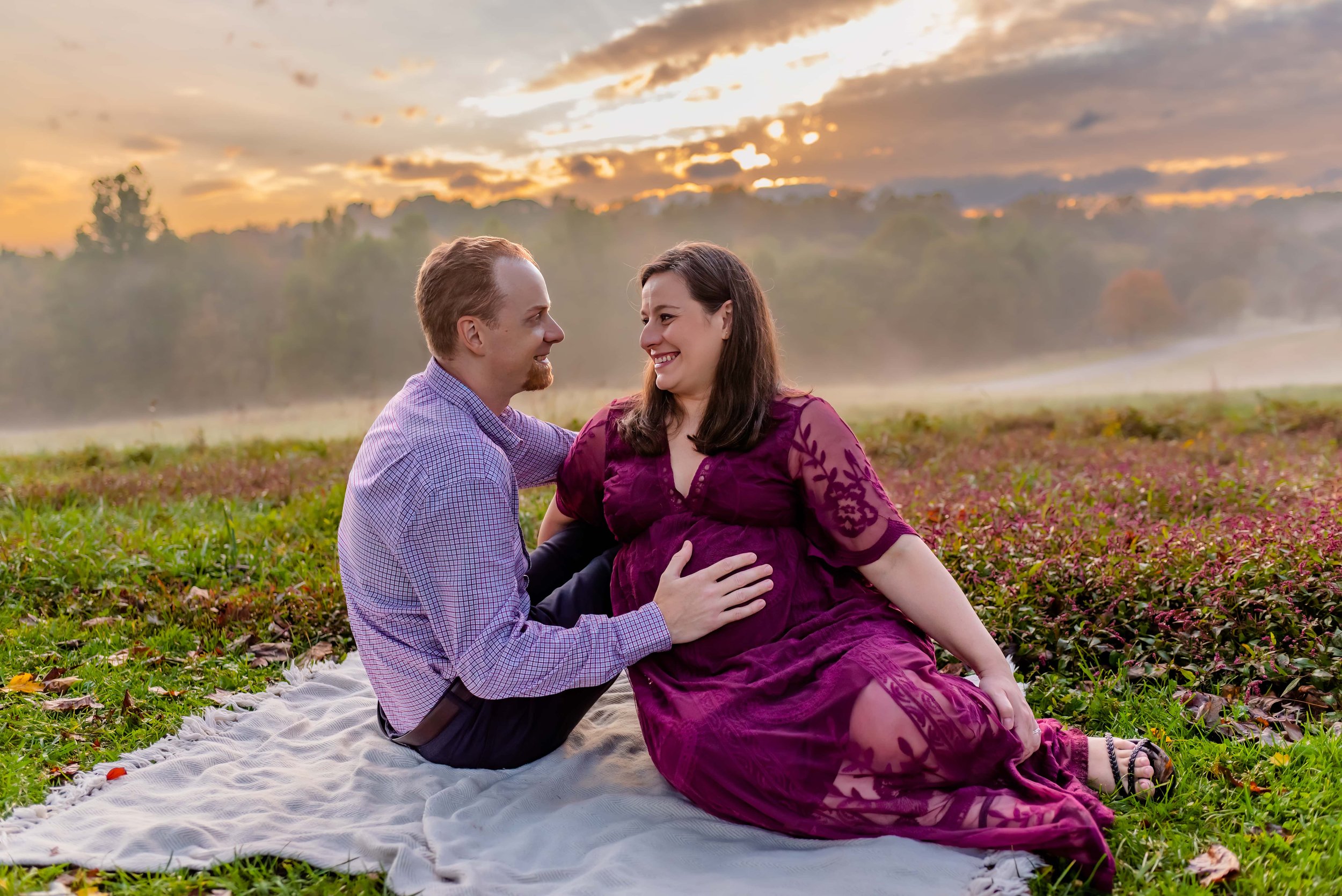 Maryland Maternity Photos - Husband and Wife Sitting in a Field smiling at each other